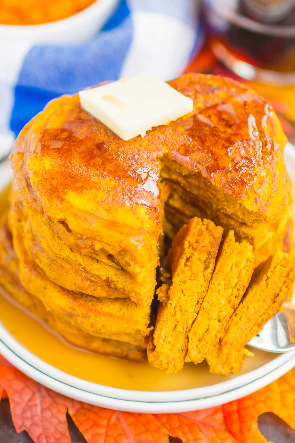 a stack of fluffy pumpkin pancakes, with a bite speared on a fork. 