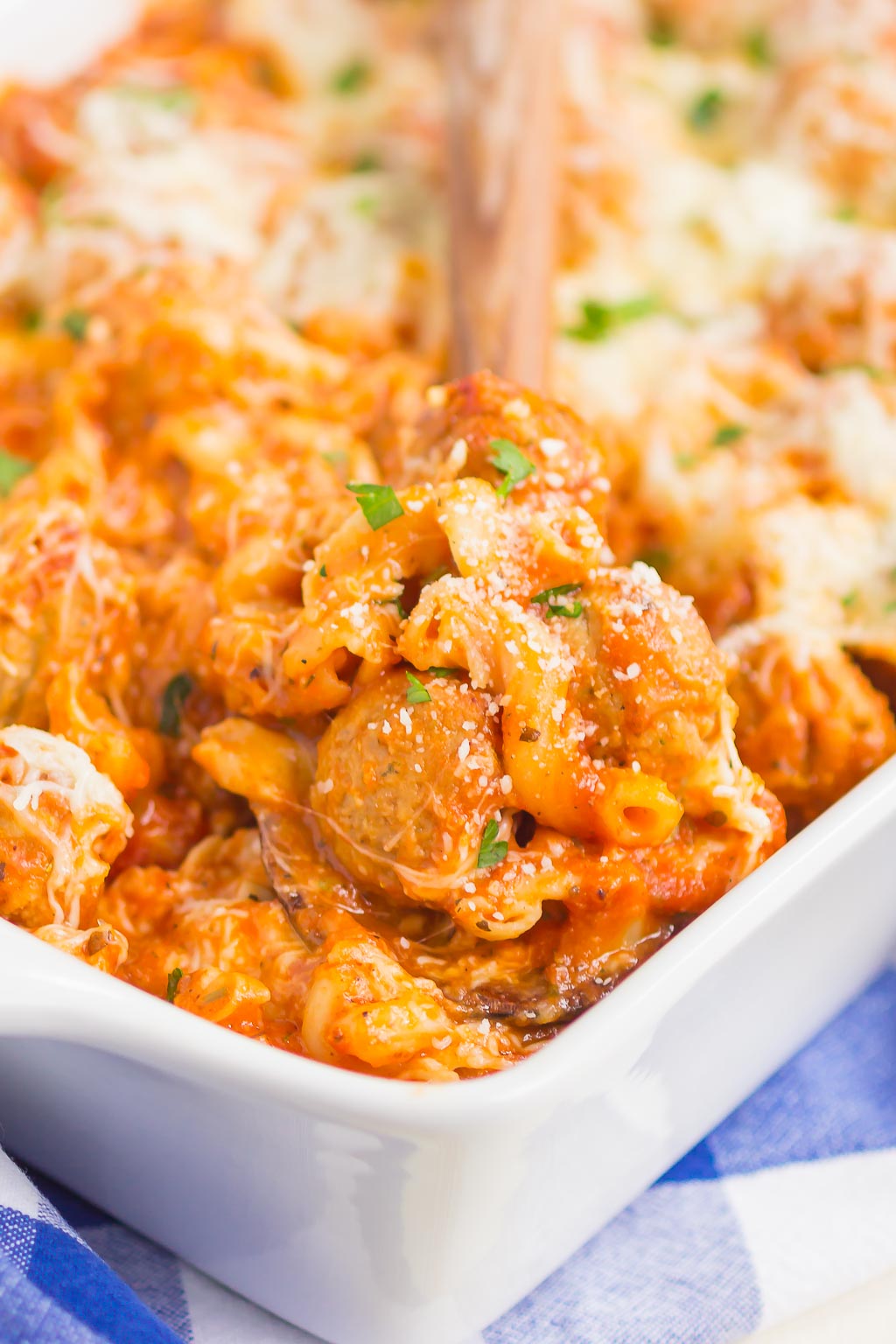 Cheesy meatball casserole being spooned out of a baking dish. 