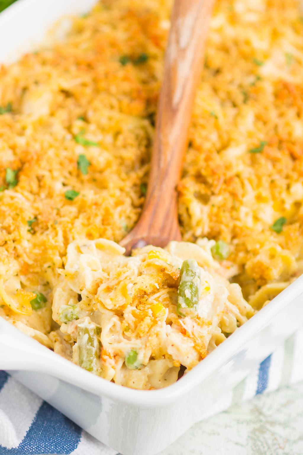 A portion of chicken and noodle casserole being scooped out of a white baking dish. 