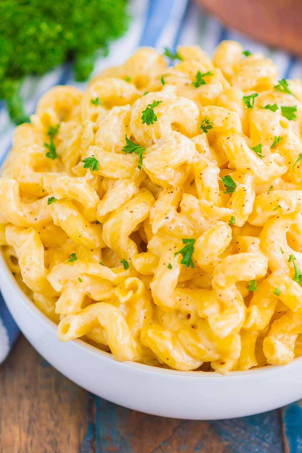 A large white bowl overflowing with creamy mac and cheese. 
