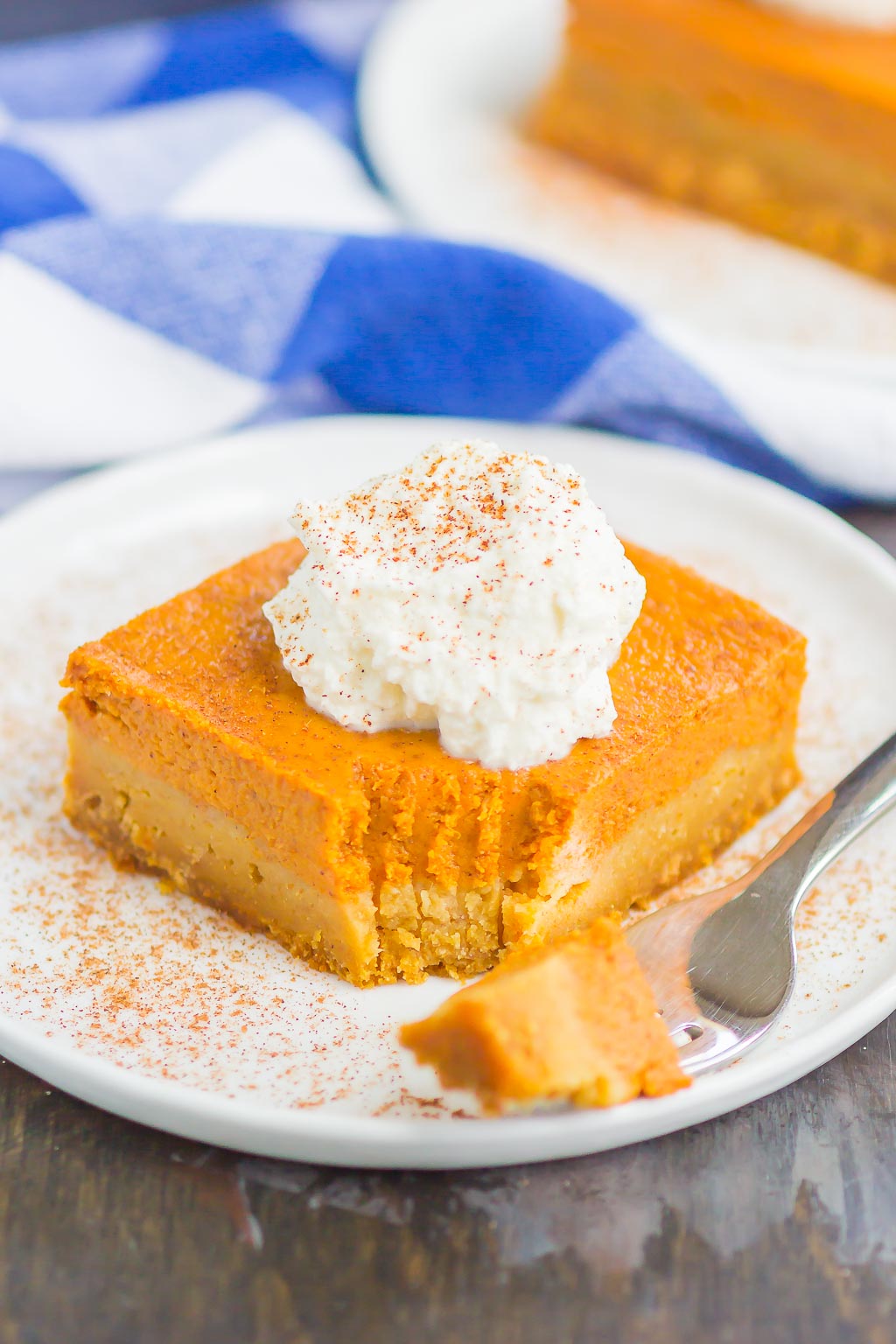 A pumpkin pie bar with a bite missing on a white plate with a fork. 