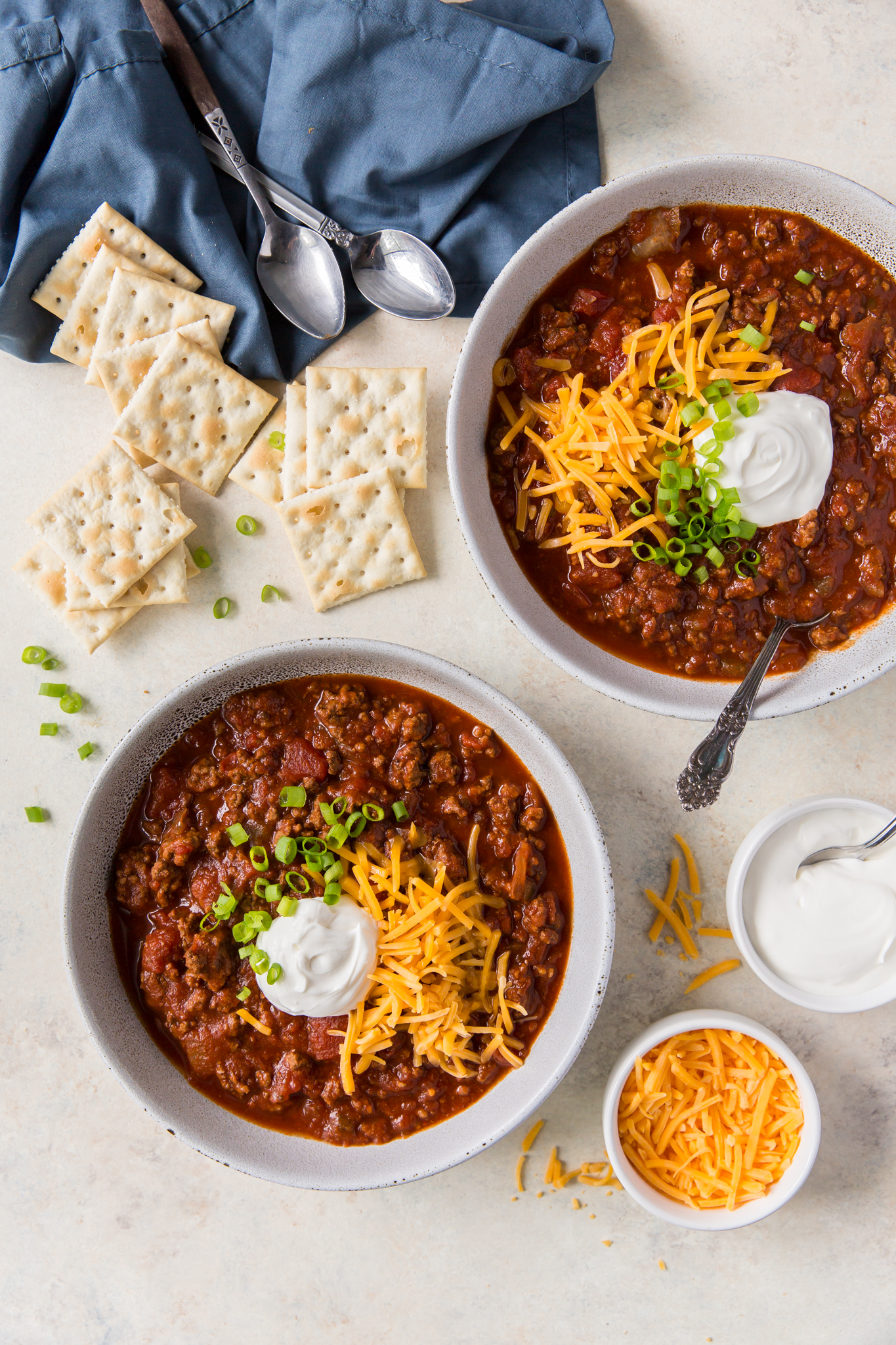 An overhead view of two bowl of beanless chili topped with garnishes. 