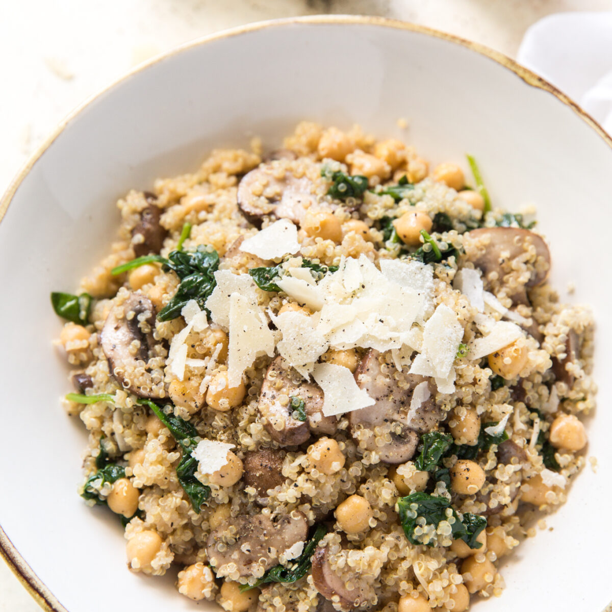 overhead view of a quinoa veggie bowl topped with shaved parmesan
