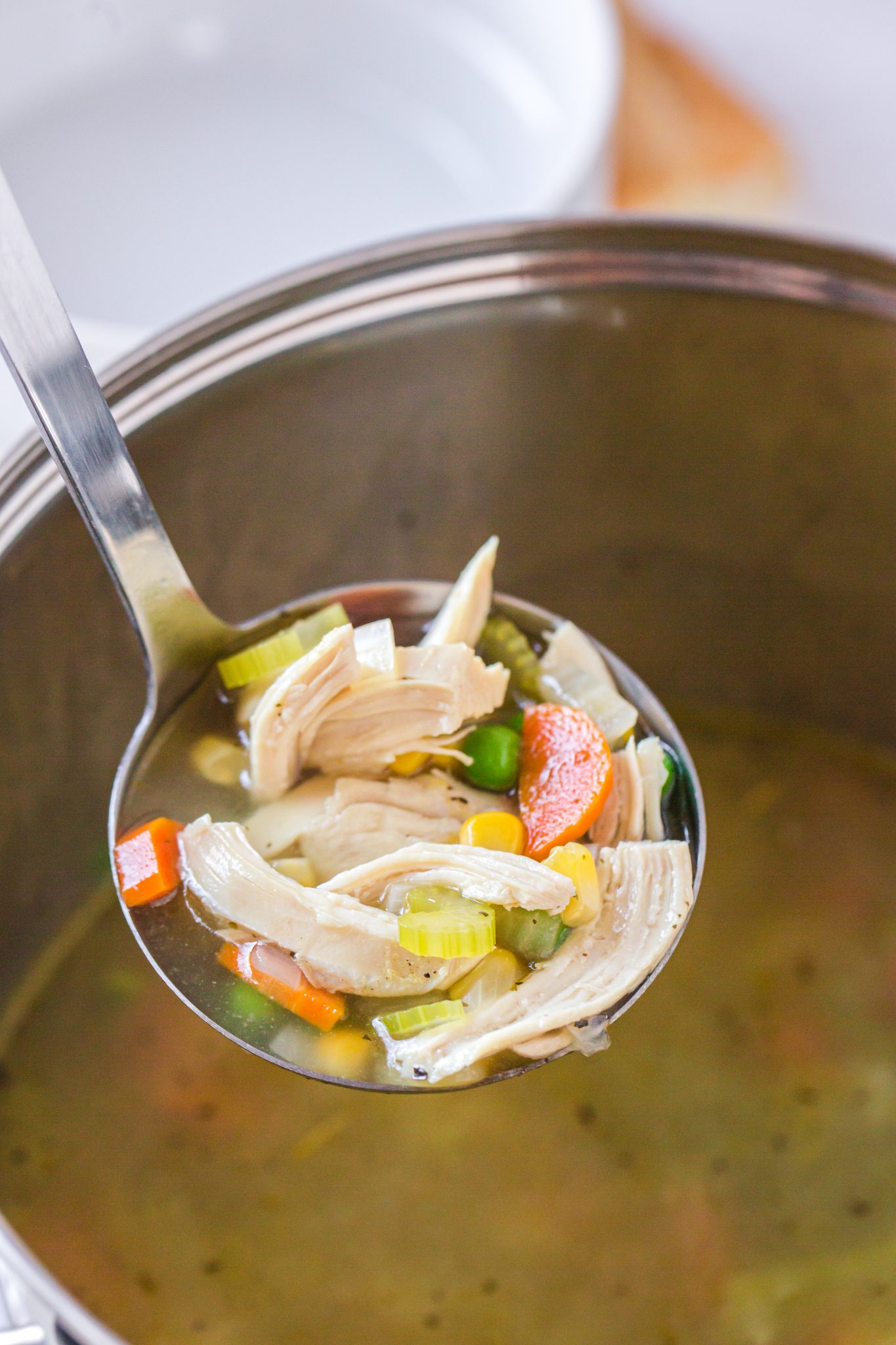 A ladle of chicken and asparagus soup being held over a soup pot