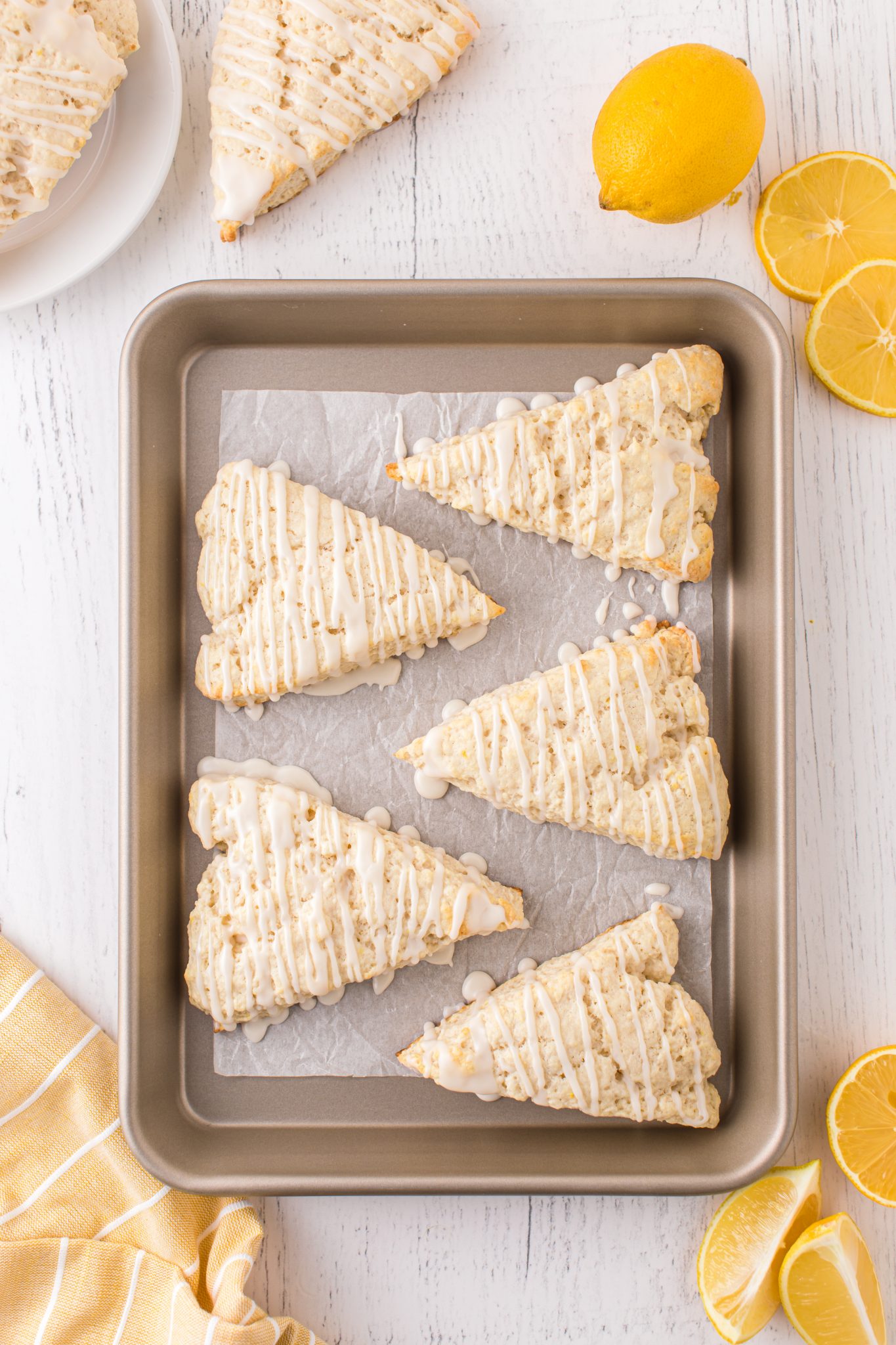 An overhead view of five lemon scones on a baking pan.