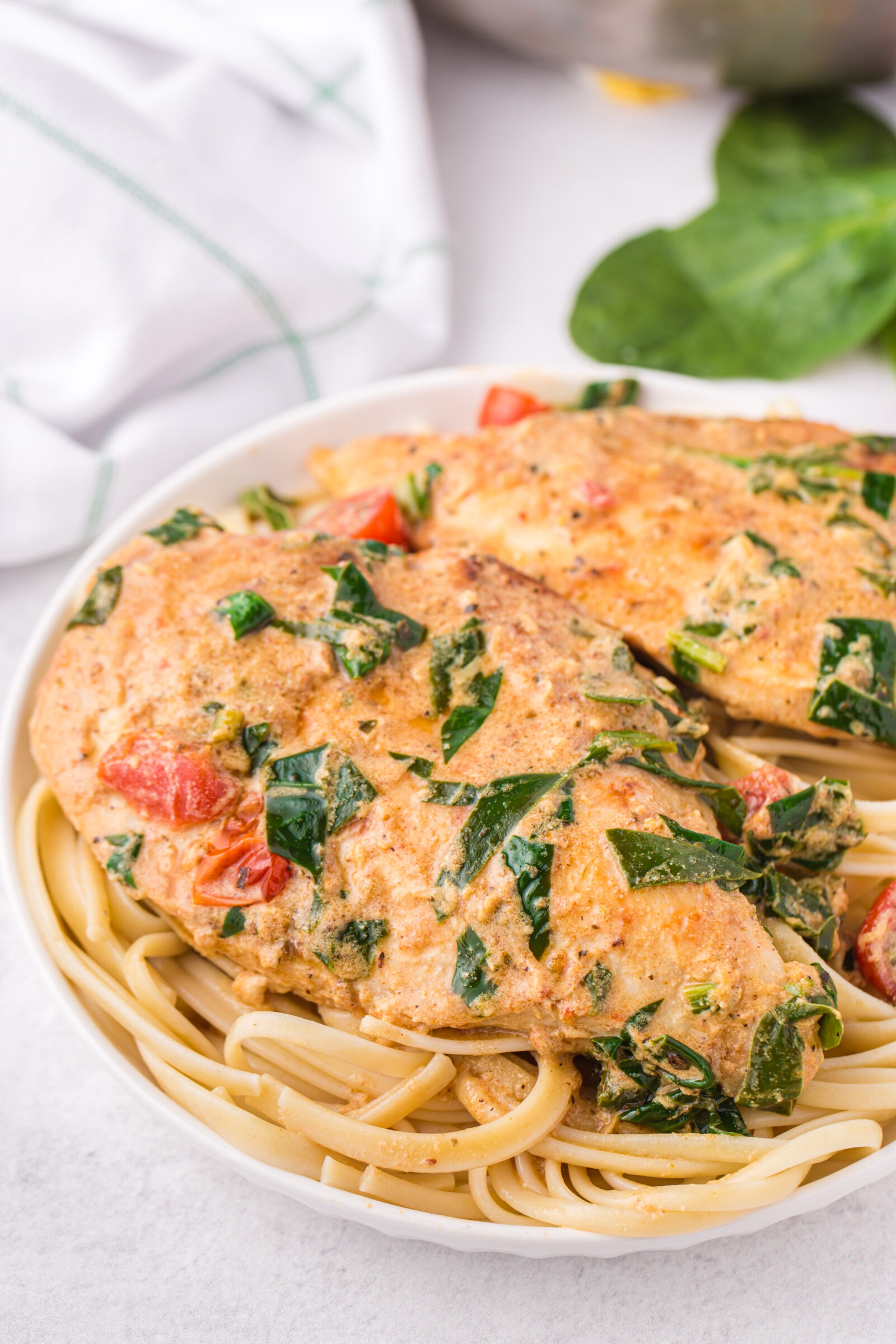 chicken over pasta on white plate