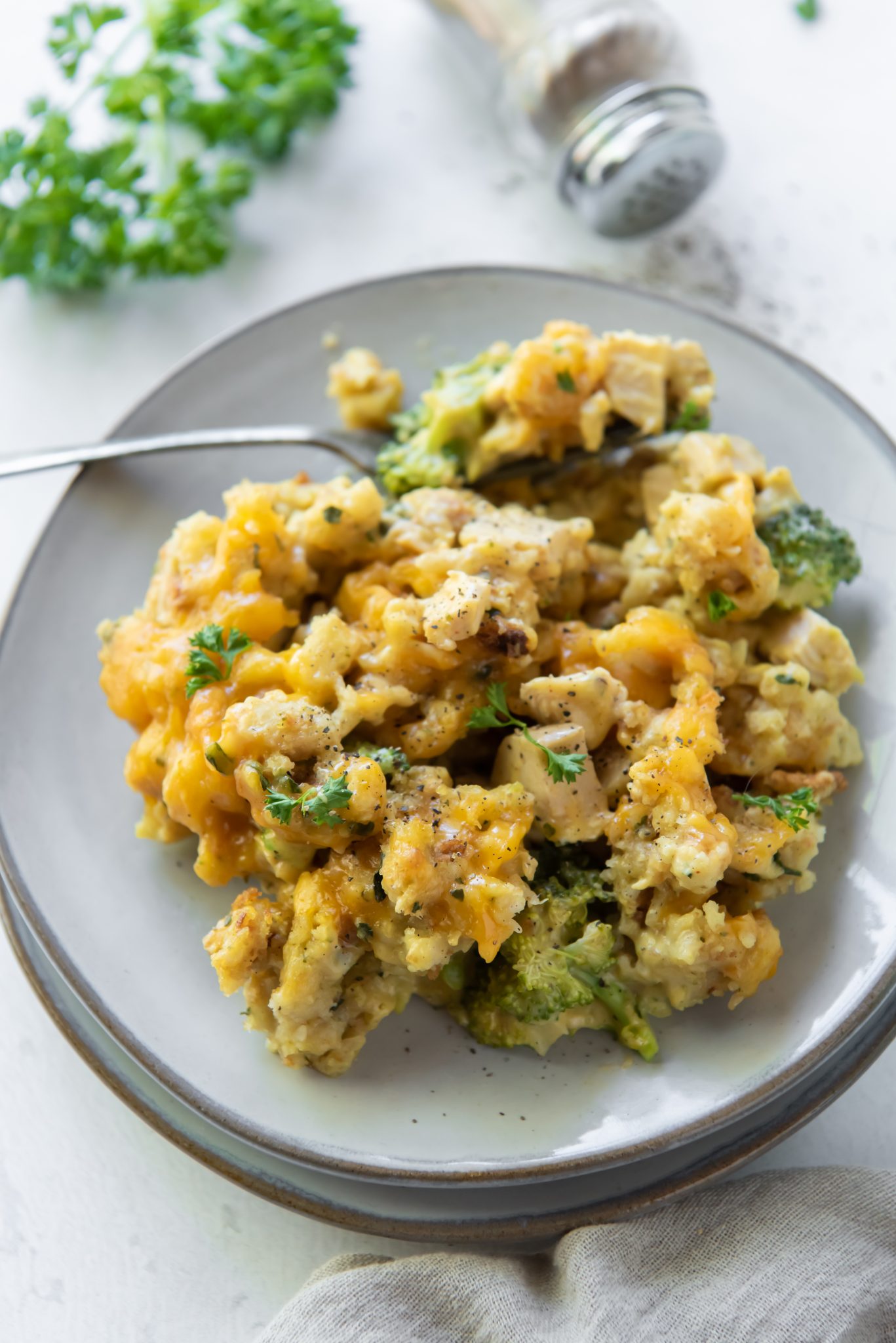 A portion of stuffing, broccoli and cheese casserole on a white plate with a fork.