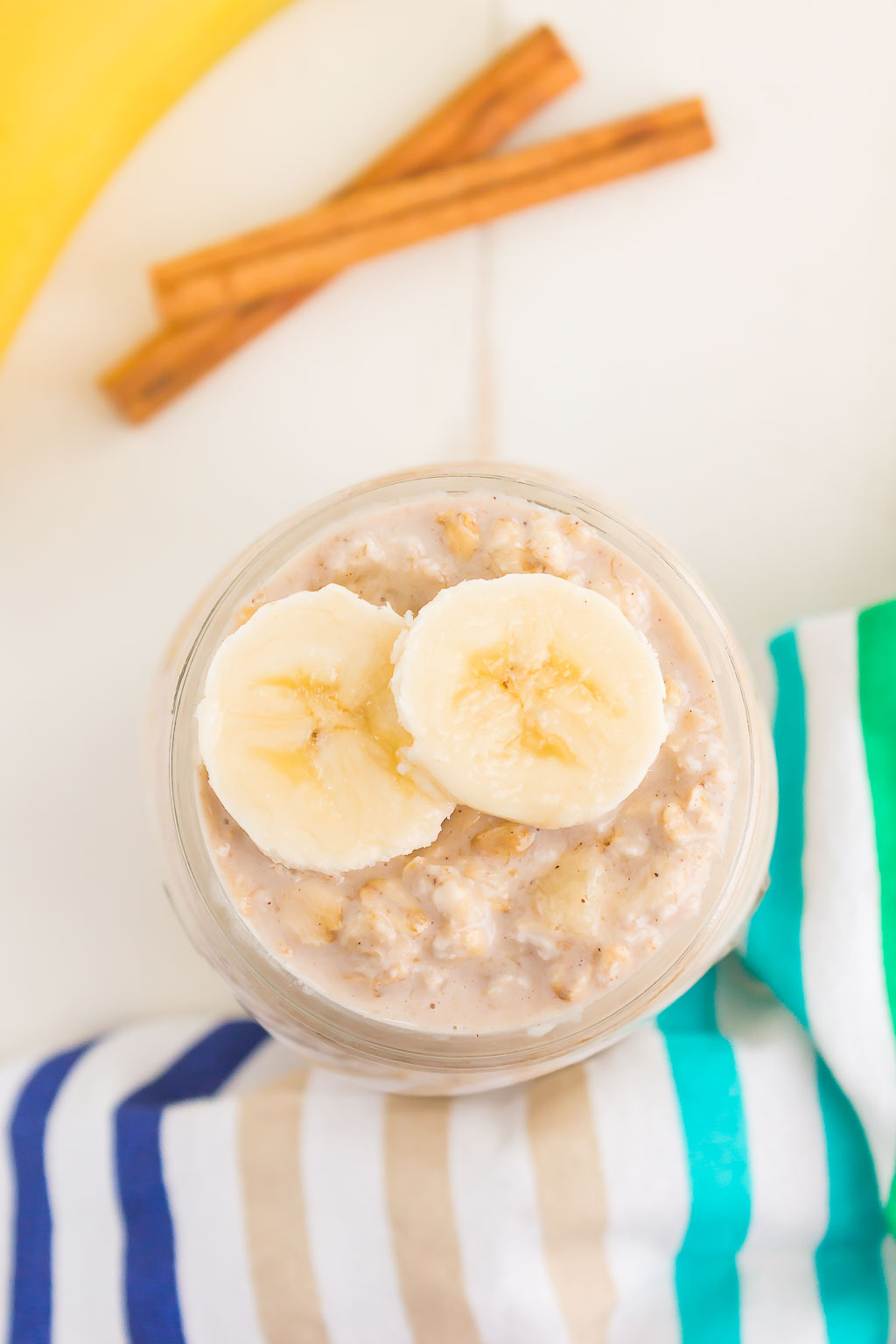 Overhead view of a mason jar of banana overnight oats topped with two banana slices. 