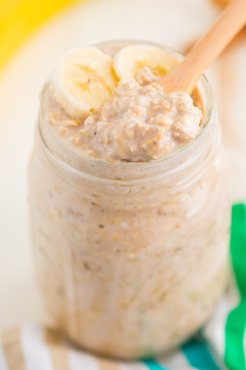 A wooden spoon digging into a jar full of banana bread overnight oats. 