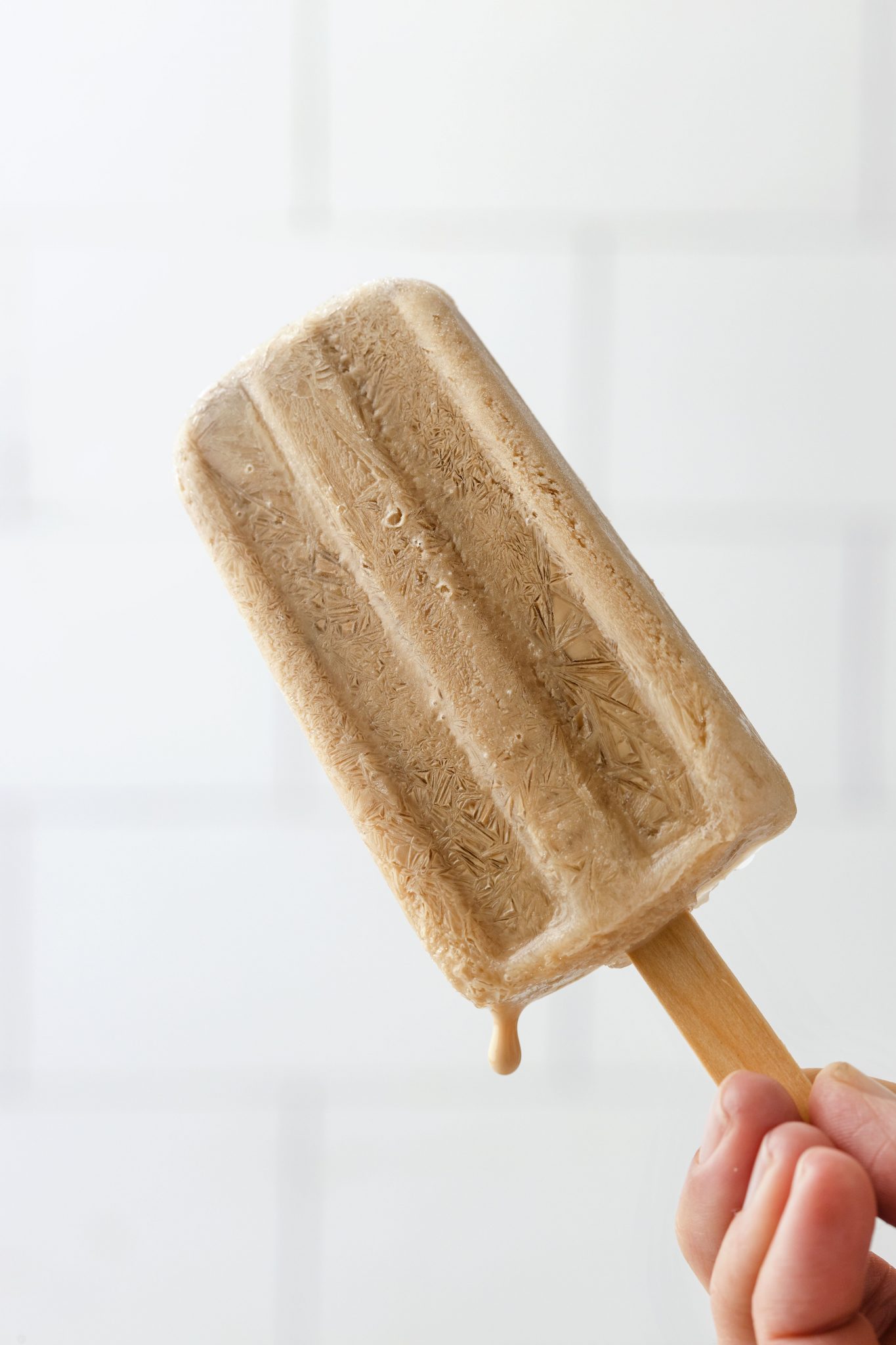 person holding pop against a white surface