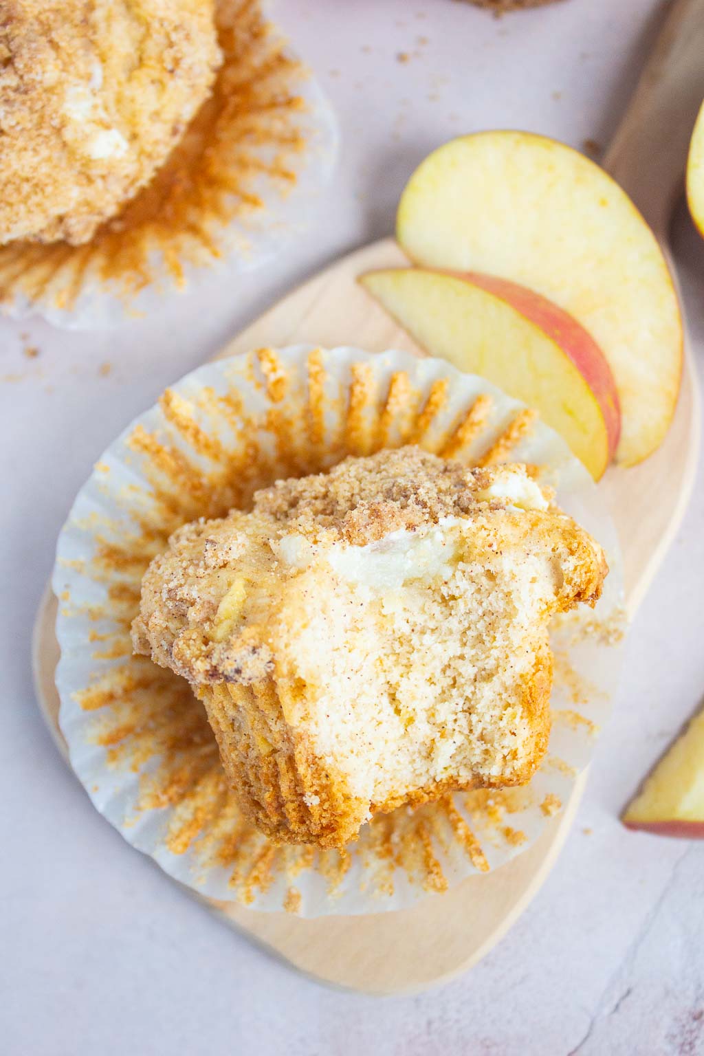 Overhead view of a cream cheese apple streusel muffin on its side, a bite is missing. 