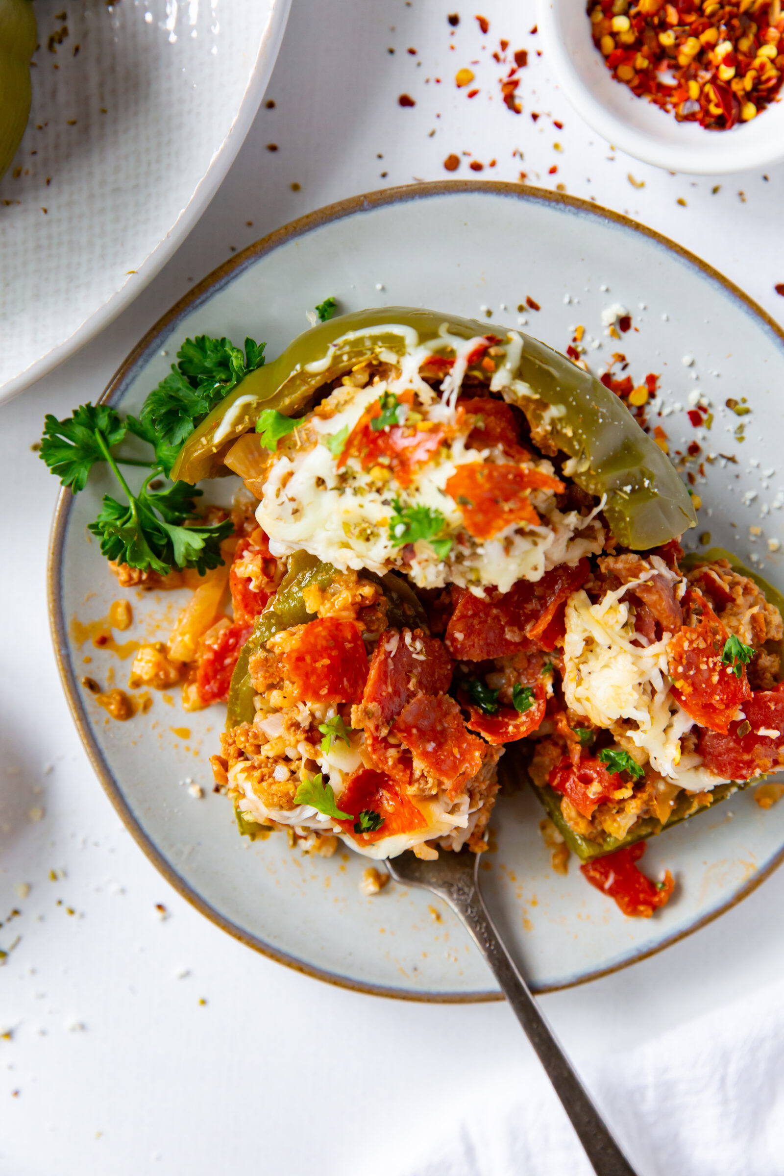 Overhead view of a partially eaten pizza stuffed pepper on a white plate. 