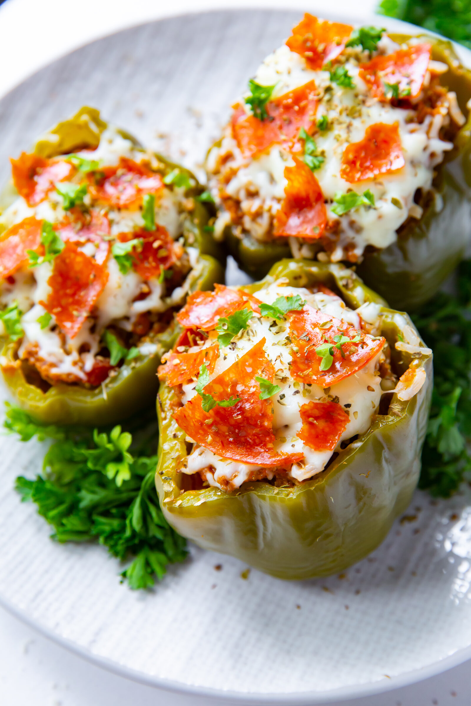 Overhead view of three pizza stuffed peppers on a plate. 