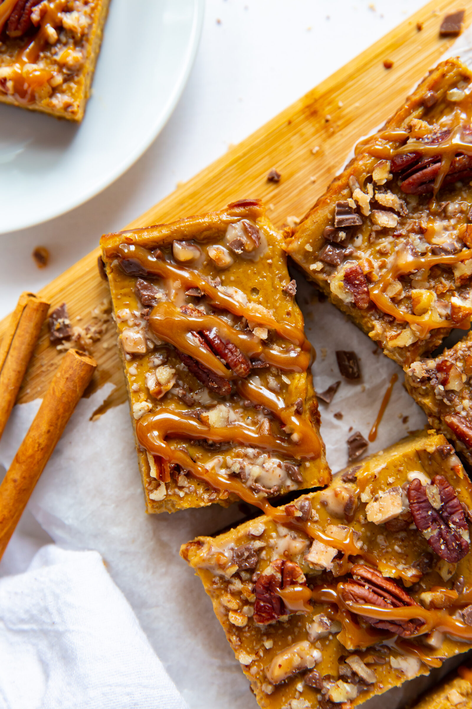 An overhead view of pumpkin pecan pie bars on a wood board. 