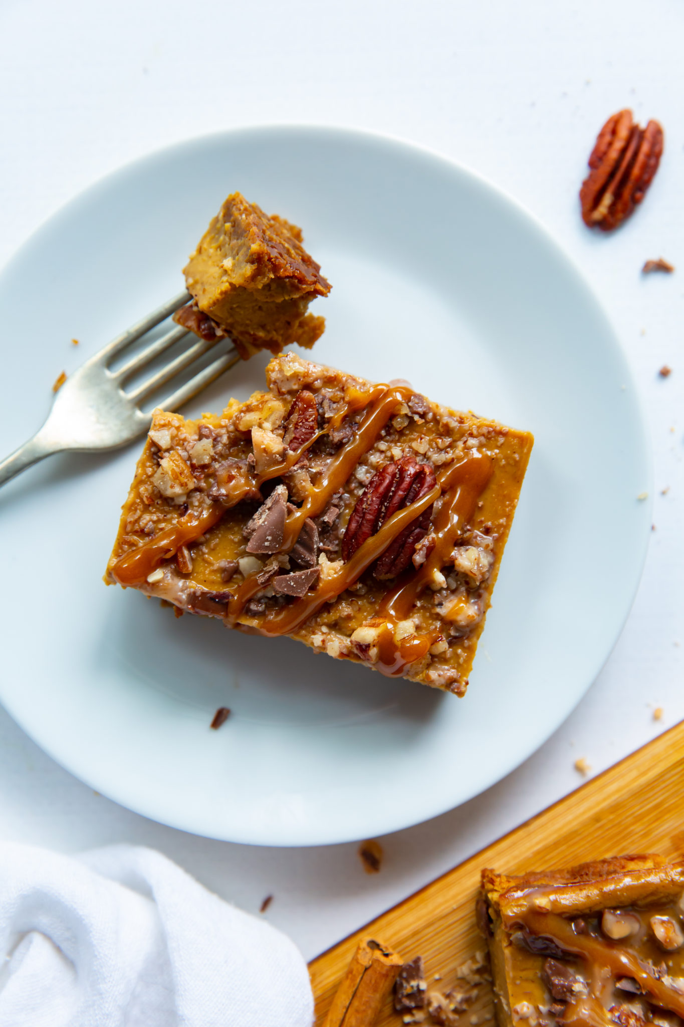 An overhead view of a pumpkin pecan pie bar on a white plate.