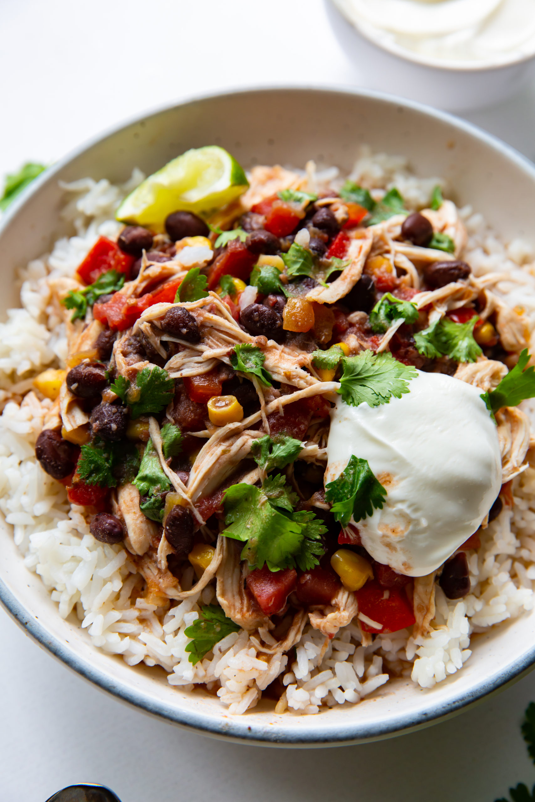 An aerial view of a bowl of Southwestern chicken and rice, garnished with sour cream and fresh cilantro.