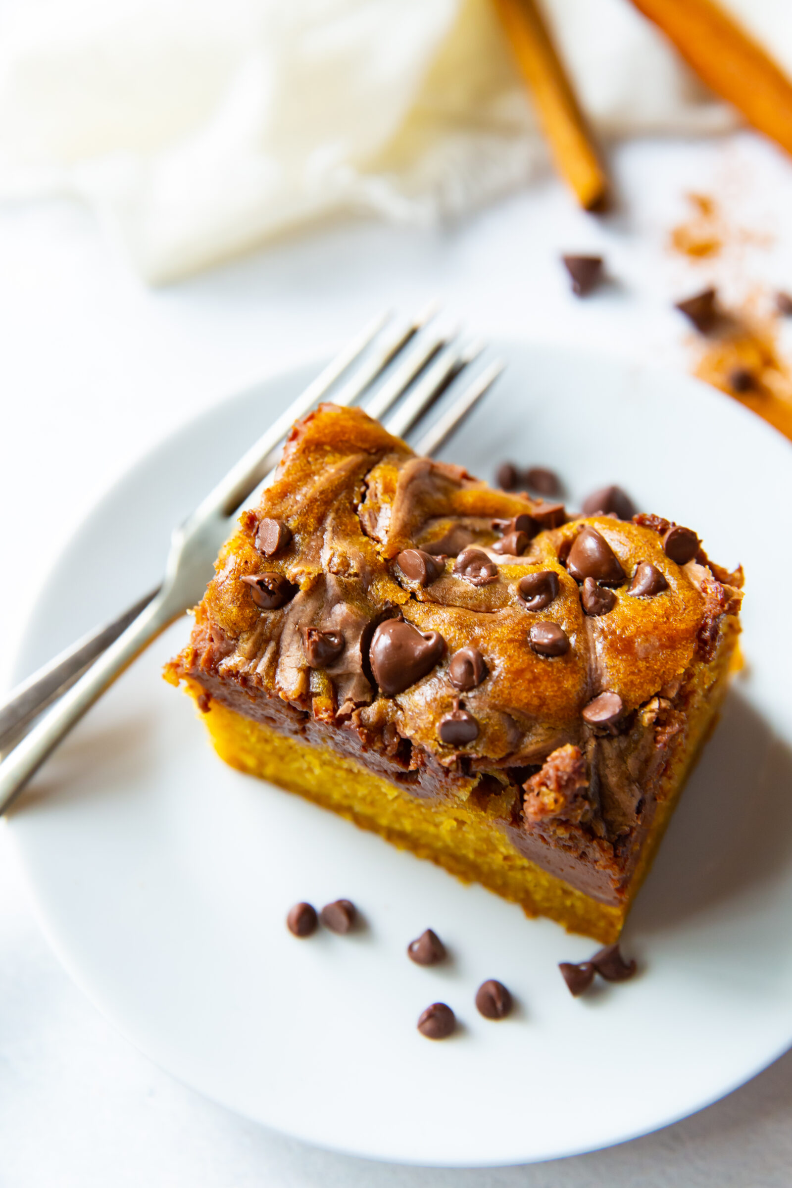 A pumpkin chocolate bar with a fork on a white plate. 