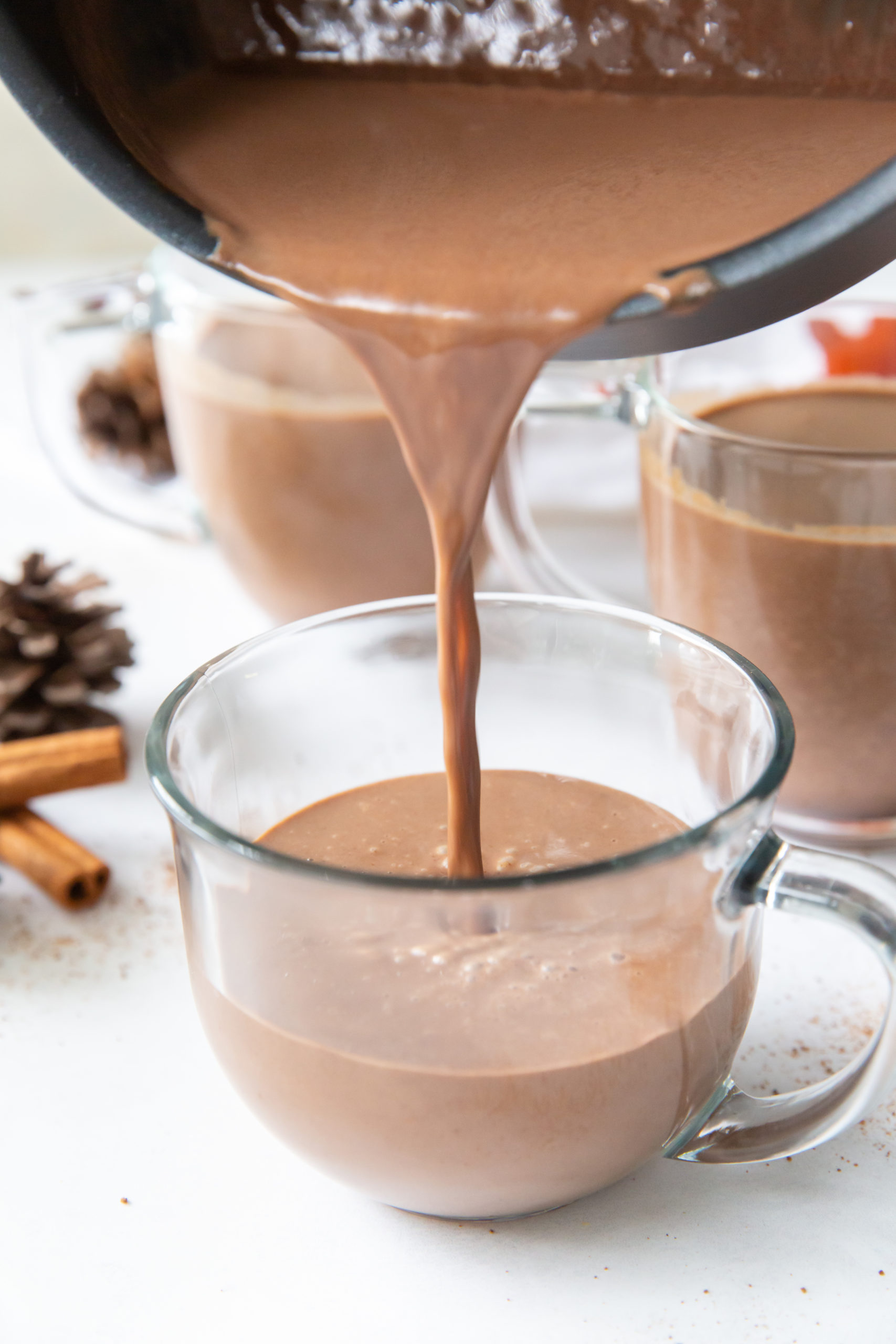Spiced hot chocolate being poured into a glass mug. 