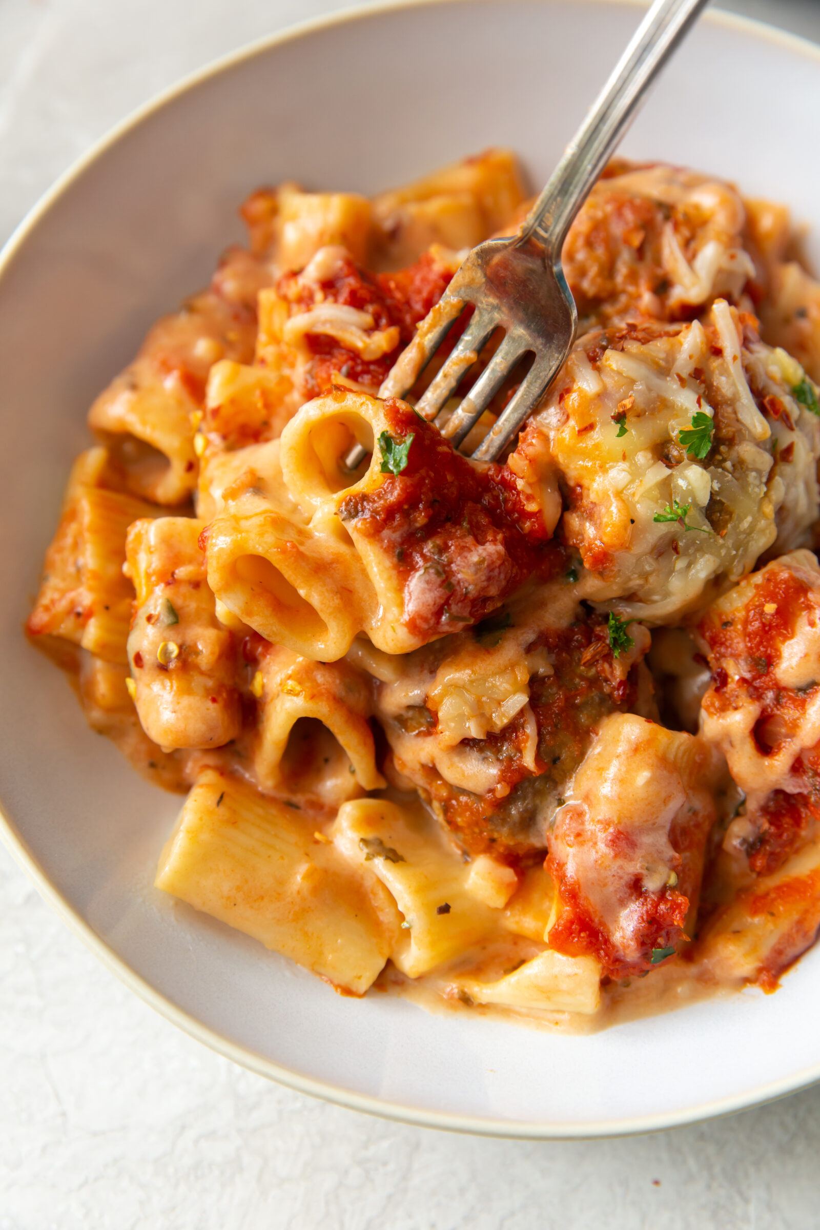 A white dish of loaded mac and cheese with meatballs. 