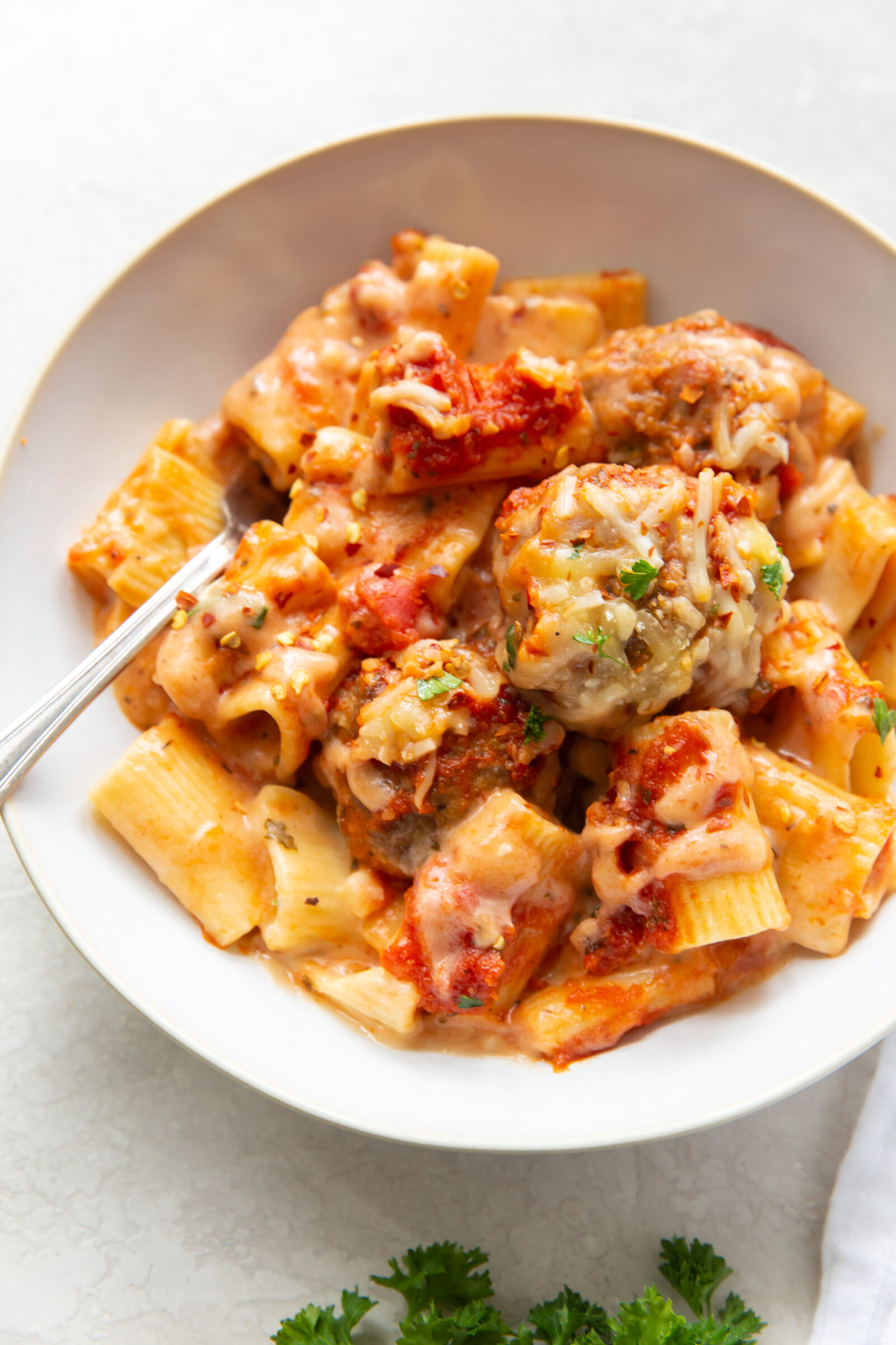 Overhead view of a bowl of fancy mac and cheese made with meatballs. 