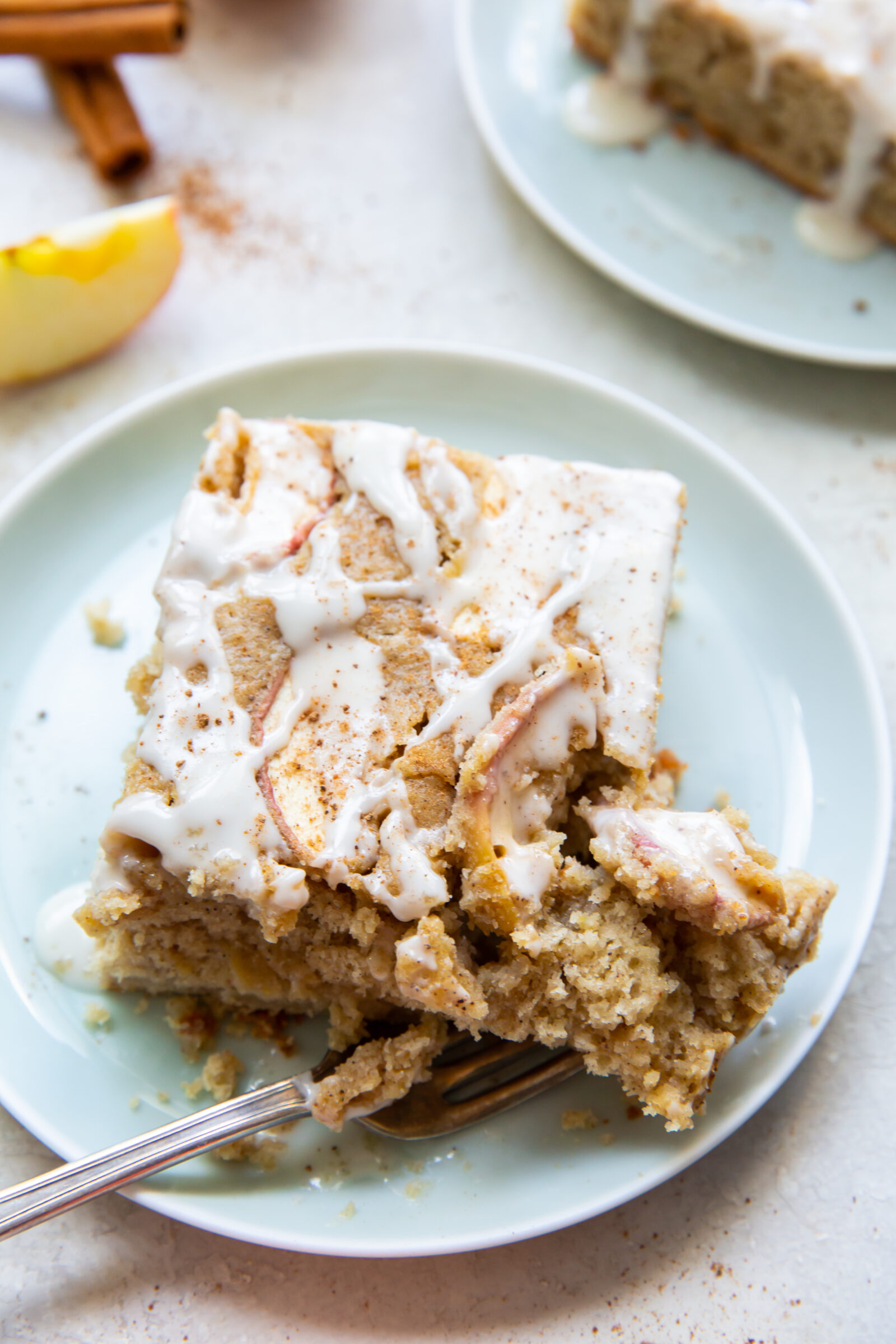 A slice of fresh apple cake topped with glaze on a light blue plate. 