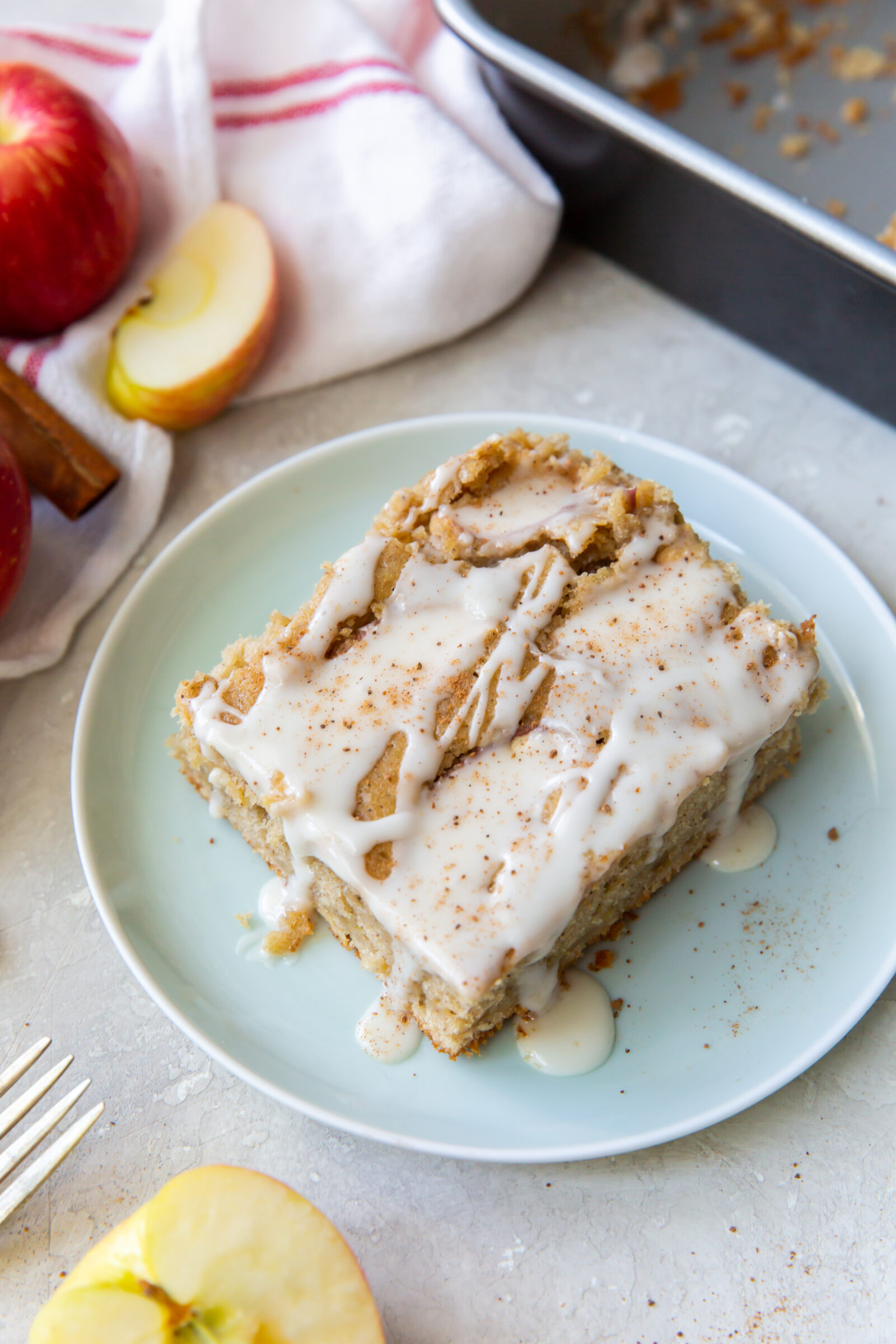 A slice of fresh apple cake topped with glaze on a light blue plate. 