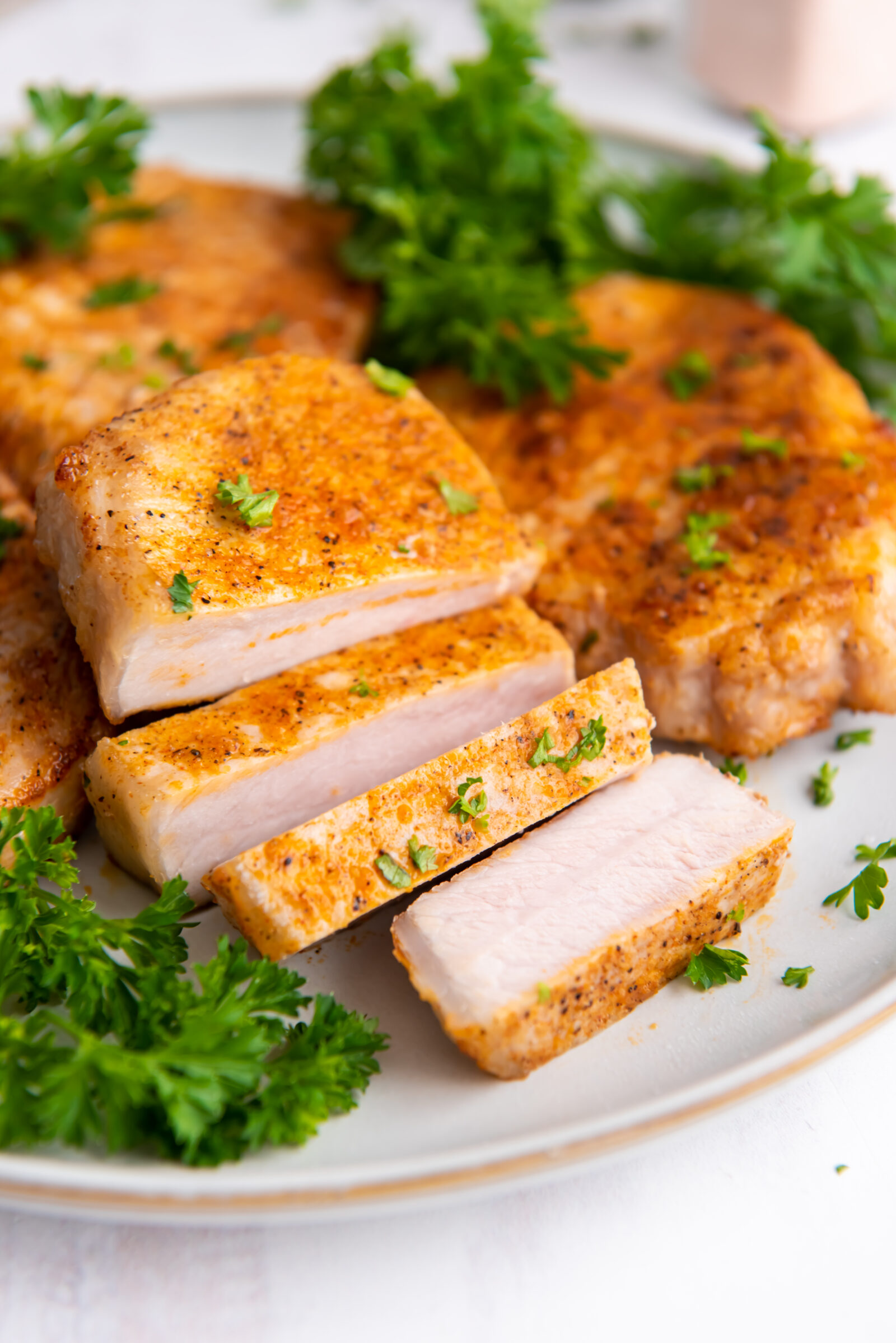 Sliced air fryer boneless pork chop with green beans on a white plate