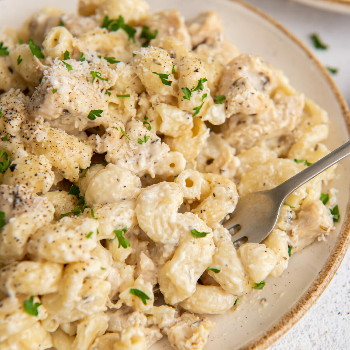 Instant Pot creamy chicken pasta on a white plate with a fork.