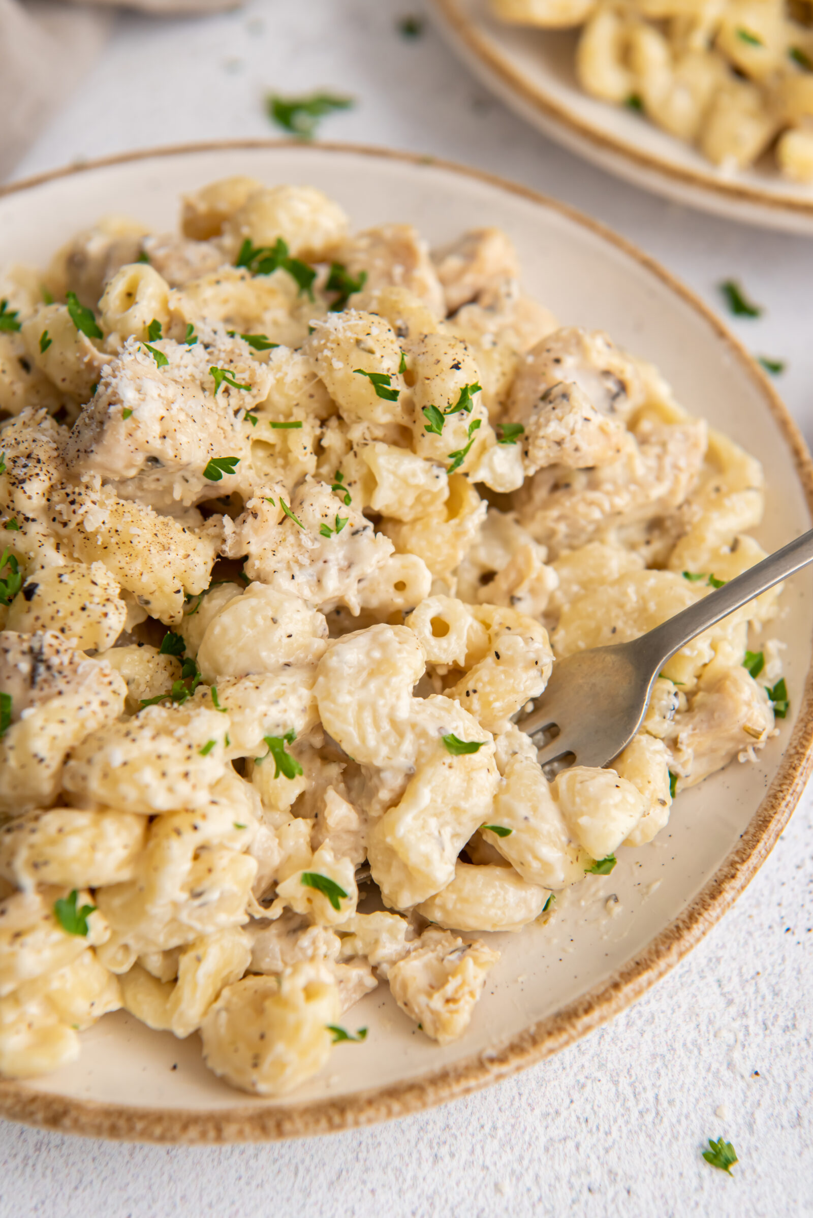 Instant Pot creamy chicken pasta on a white plate with a fork. 