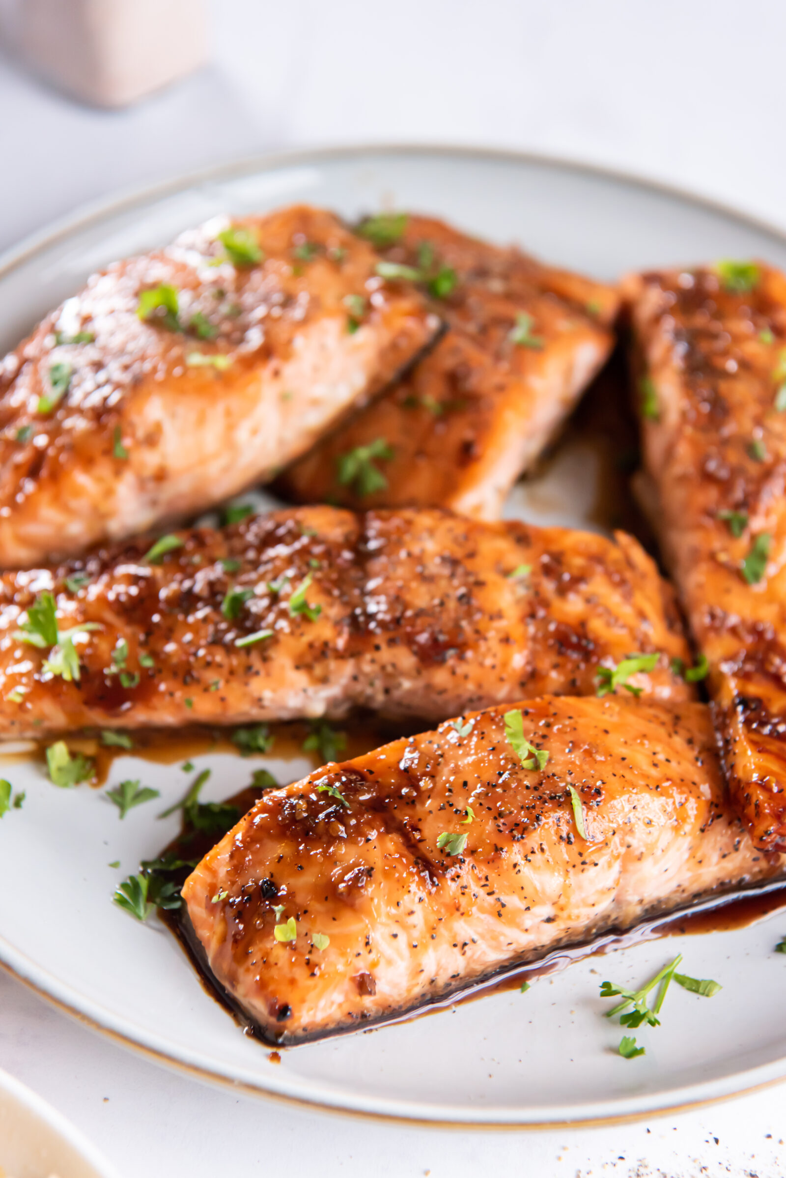 Five maple soy salmon filets on a white plate. 