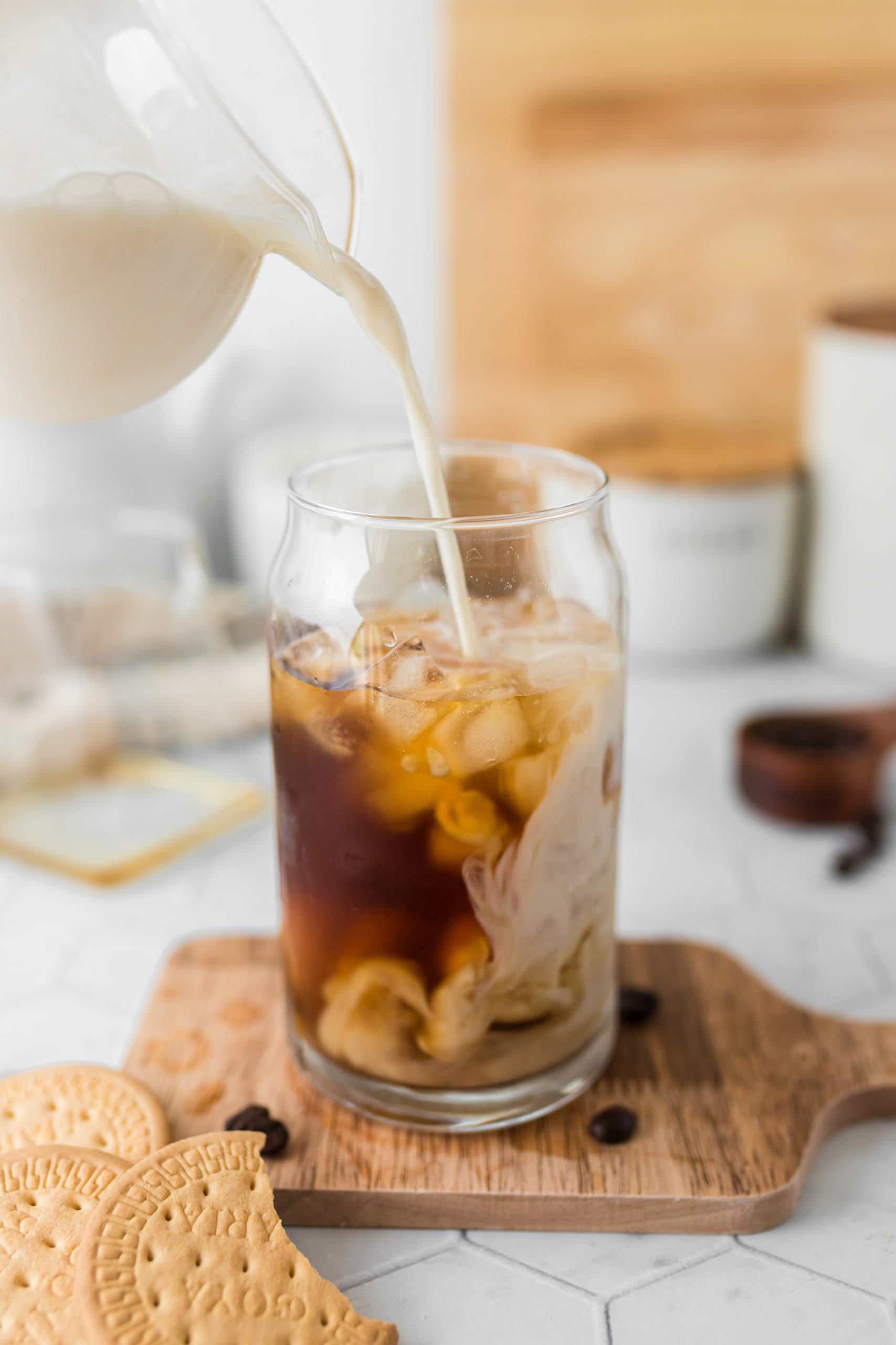 Milk being poured into a glass of iced coffee to make a caramel iced latte. 