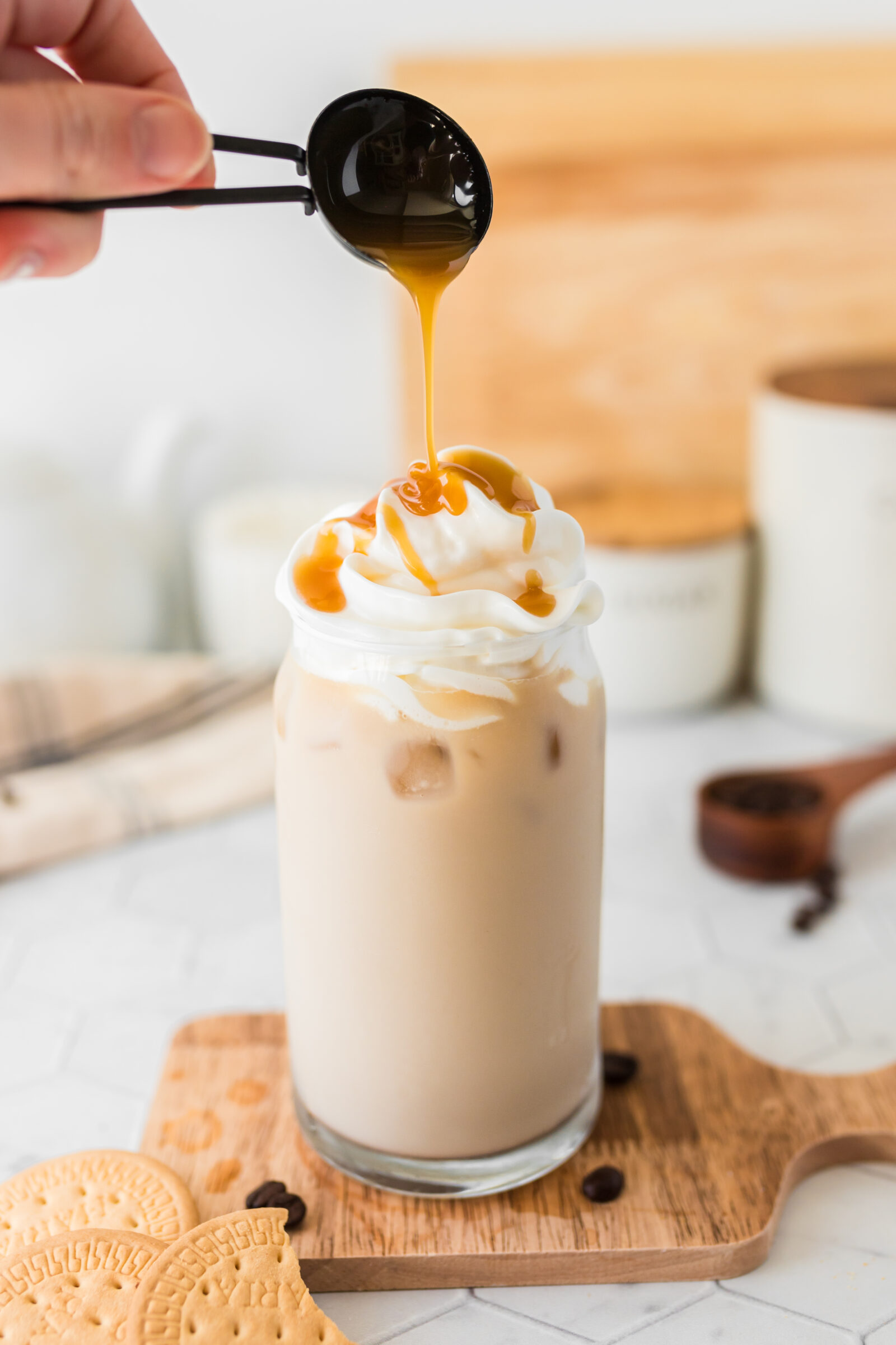 Caramel sauce being drizzled over the top of a salted caramel iced latte. 