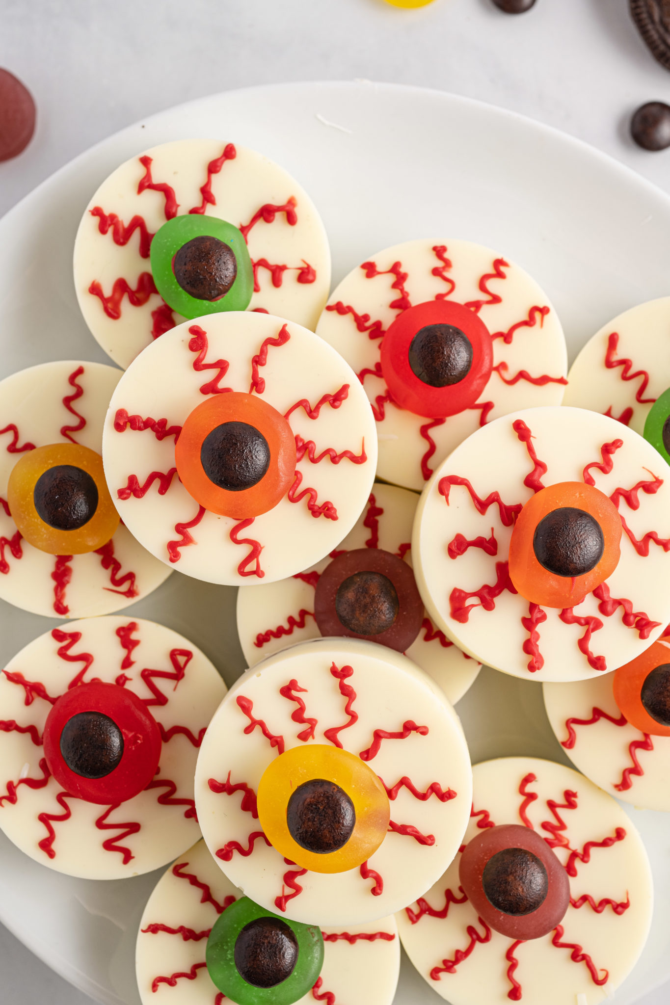 An overhead view of Halloween chocolate covered Oreo eyeballs on a white plate.