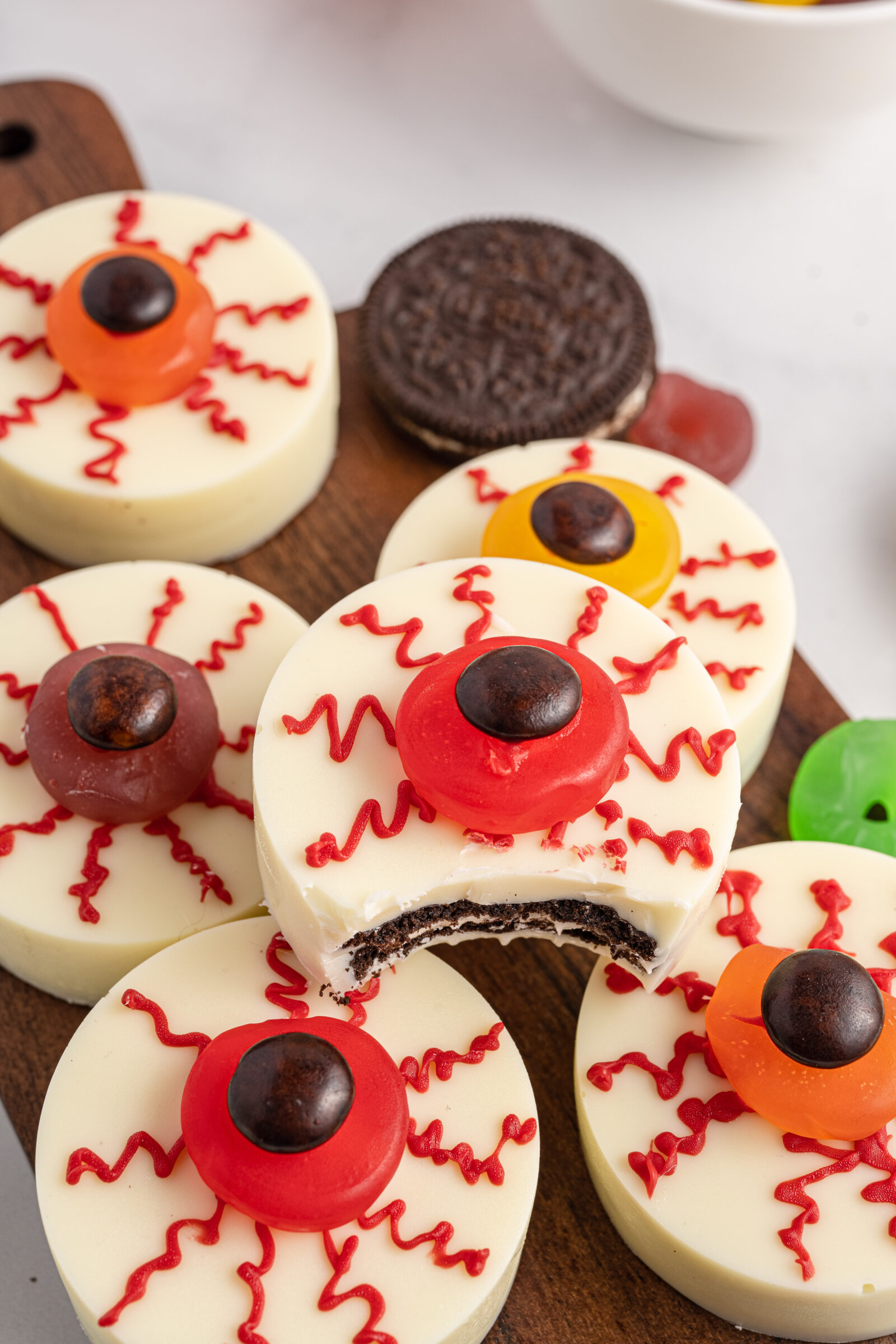 Oreo eyeballs on a cheese board. One Oreo has a bite missing. 