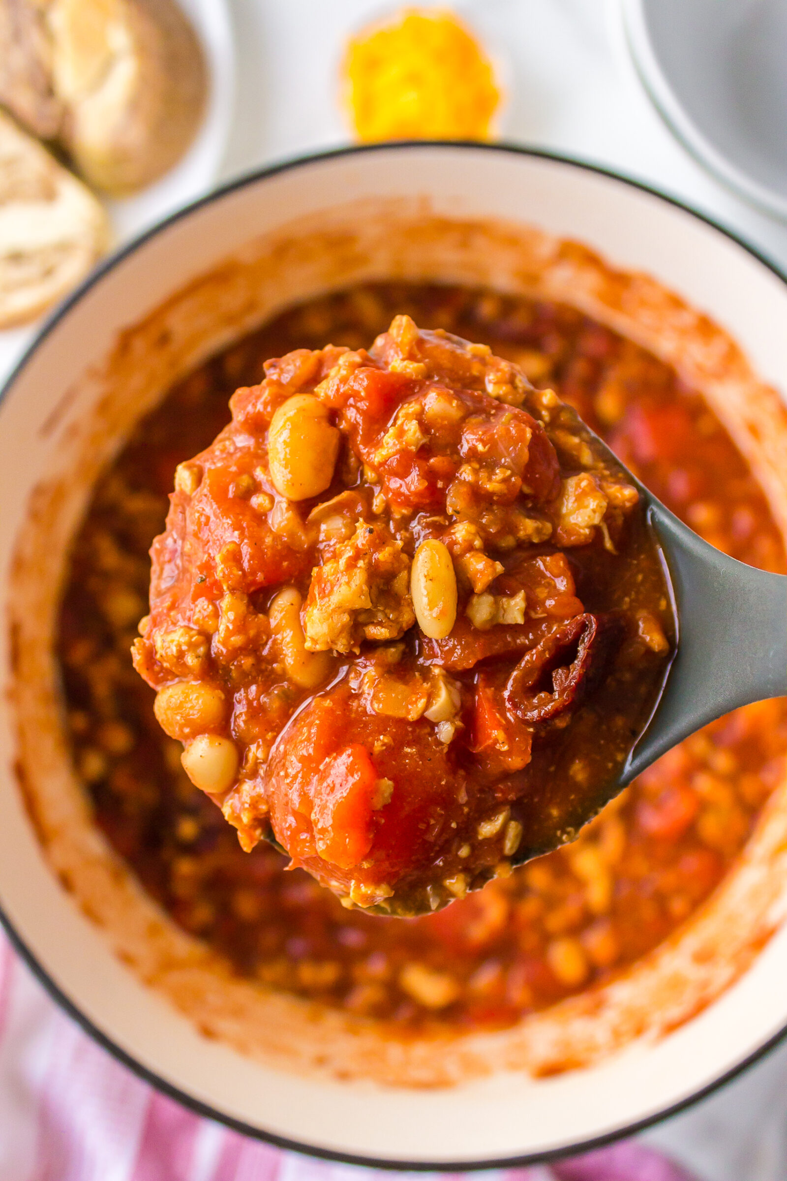 An overhead view of a ladle full of turkey white bean chili. 