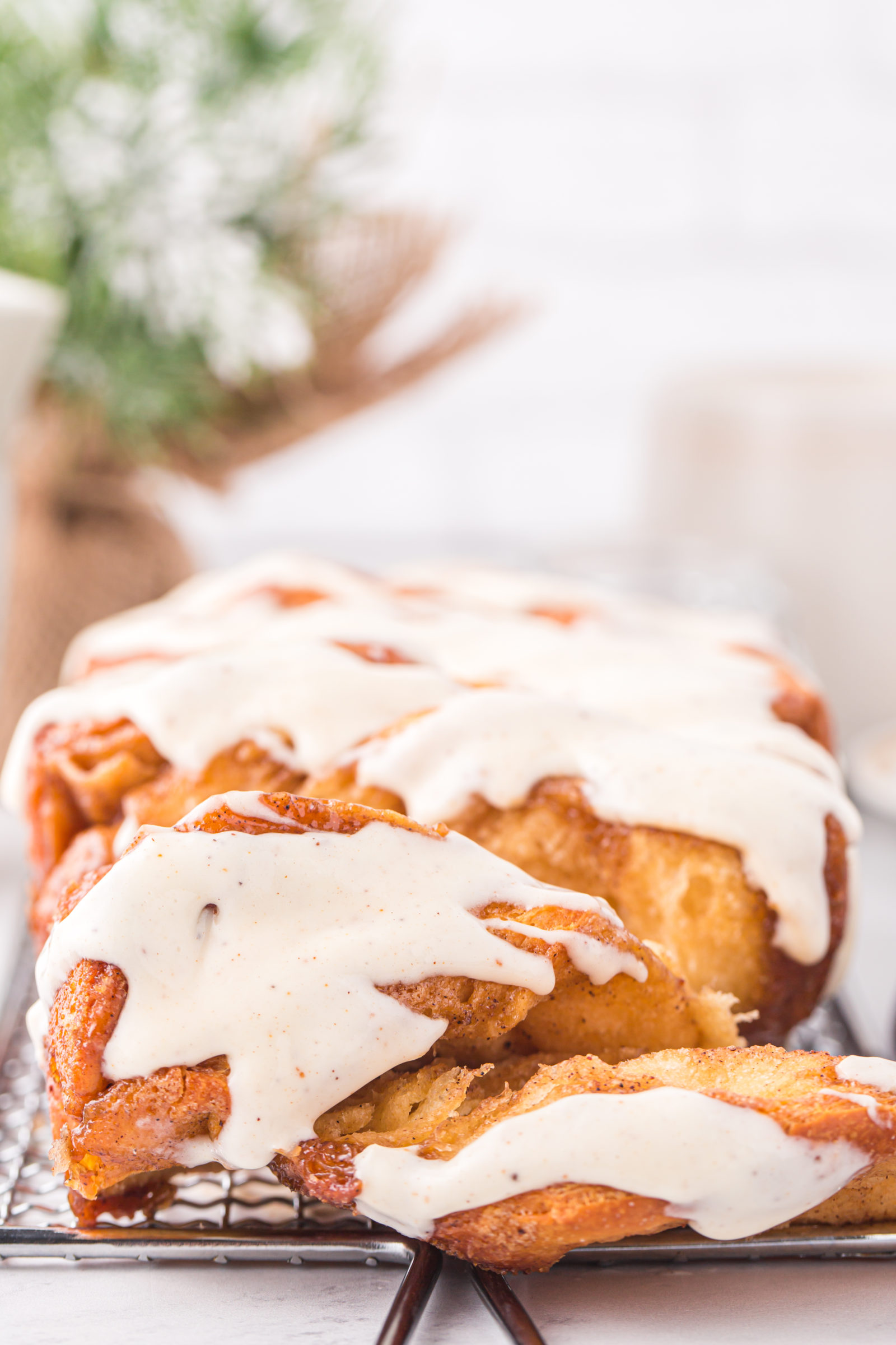 A loaf of glazed eggnog pull-apart bread on a wire rack. 