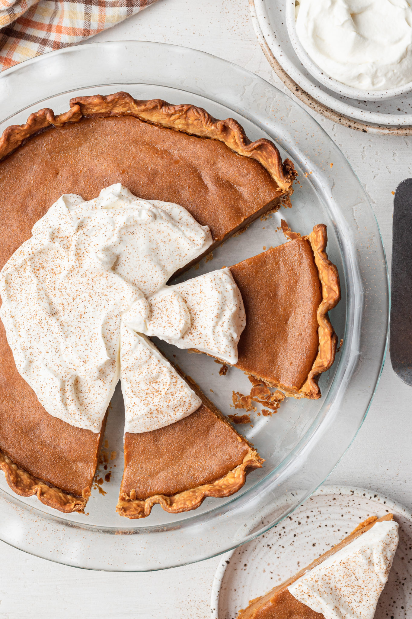 overhead pie on a transparent plate with whipped cream on top and fork on the side
