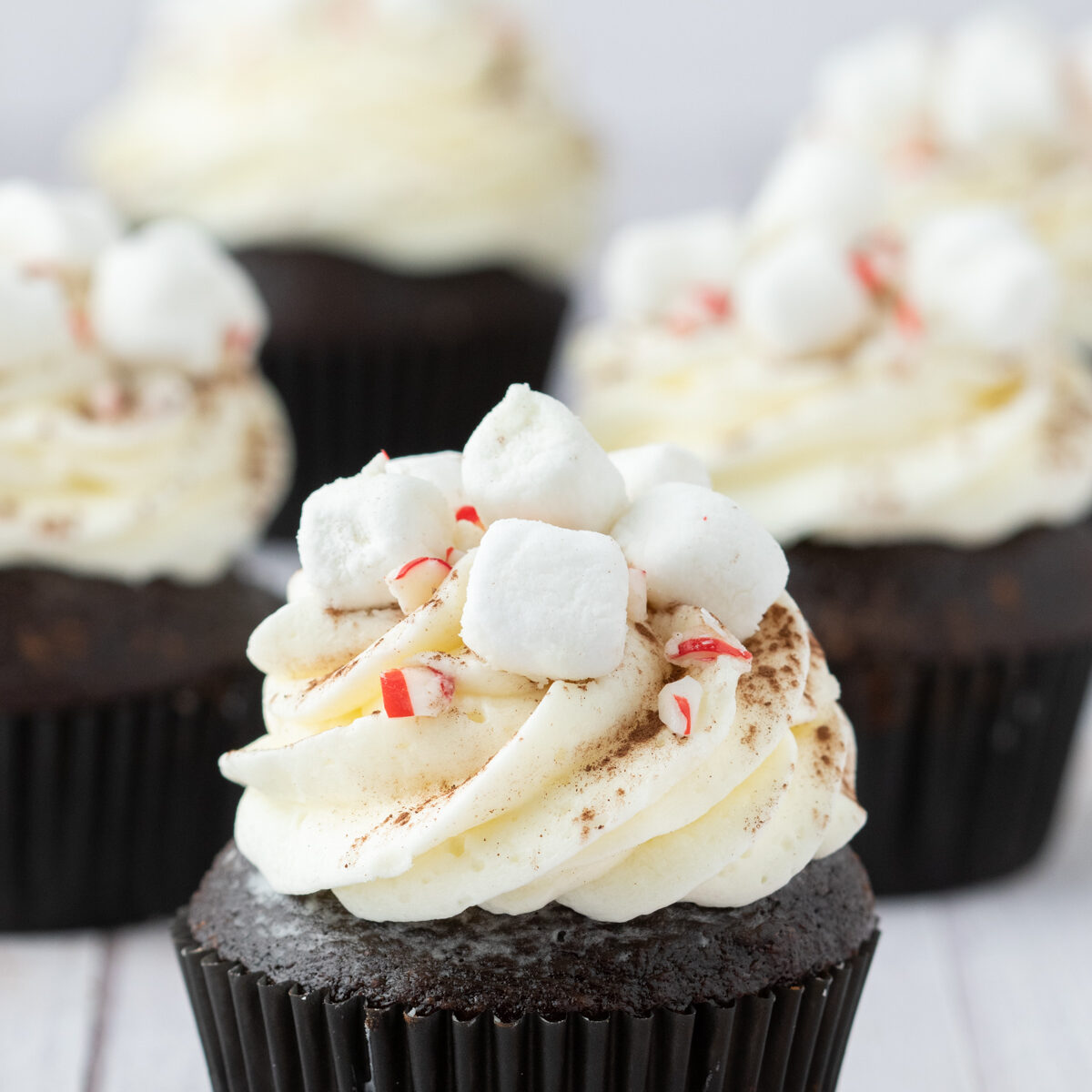 Four hot chocolate cupcakes topped with marshmallow buttercream frosting. 