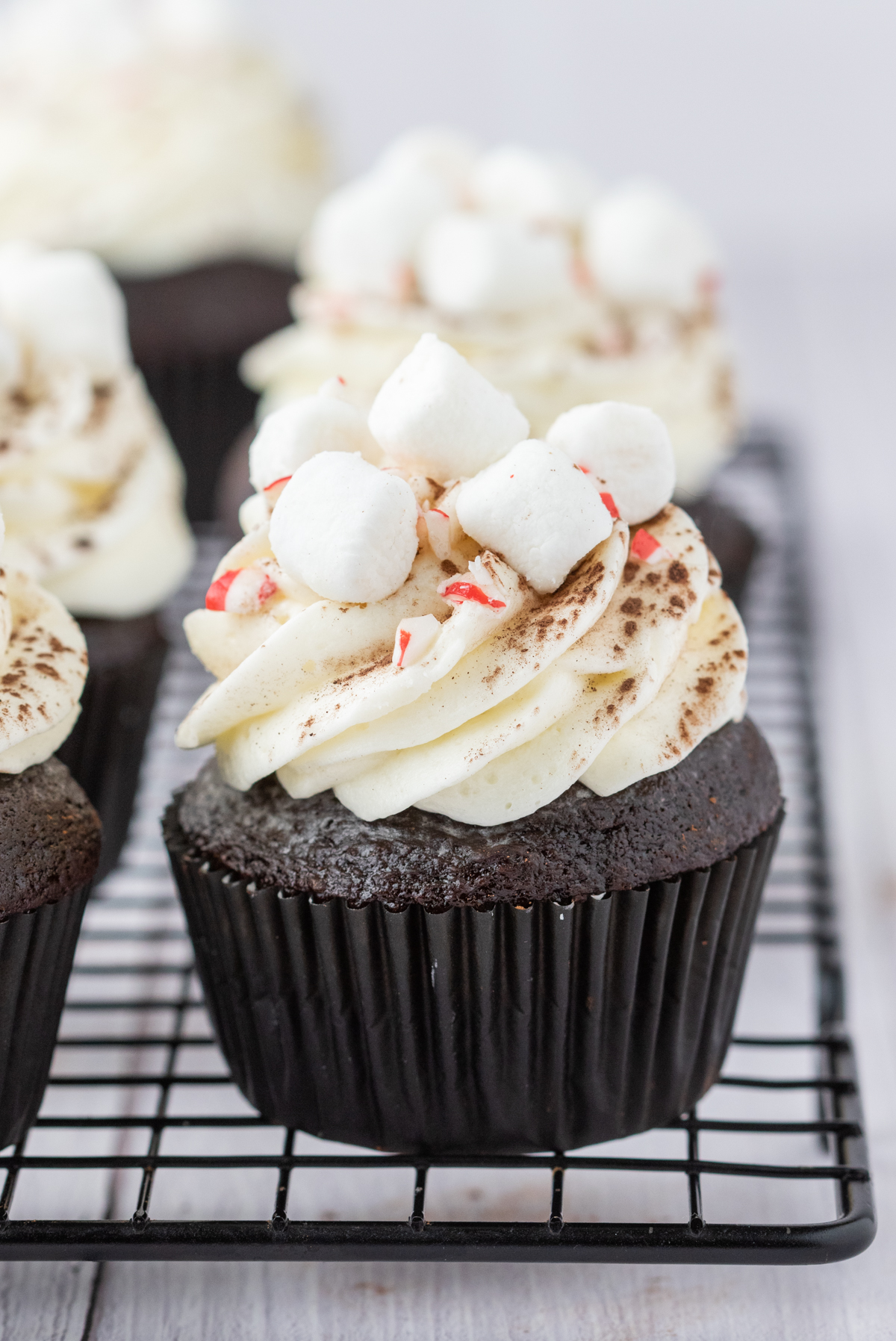 Frosted hot cocoa cupcakes on a wire cooling rack. 