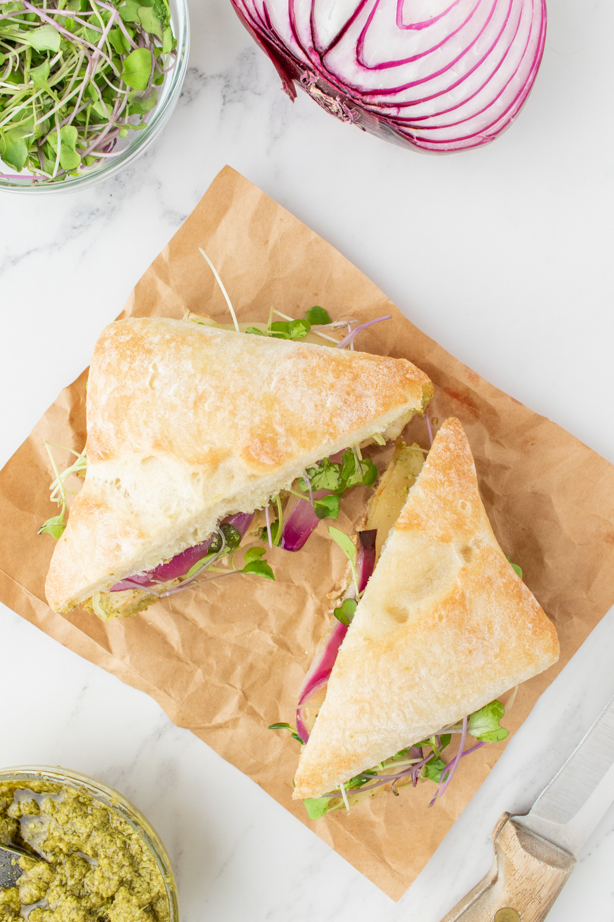 Overhead view of a pesto chicken mozzarella sandwich, cut in half. 