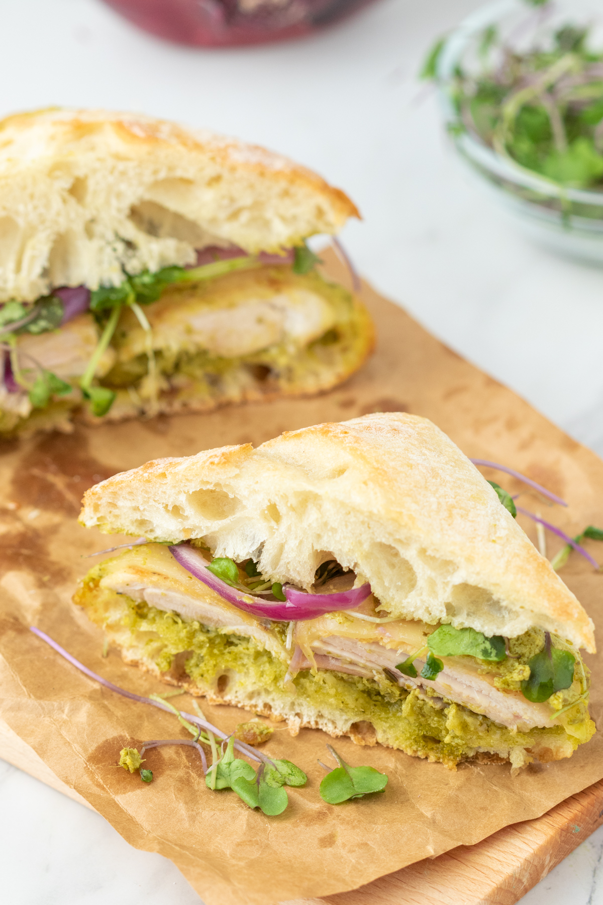 Two halves of a chicken sandwich with pesto. 