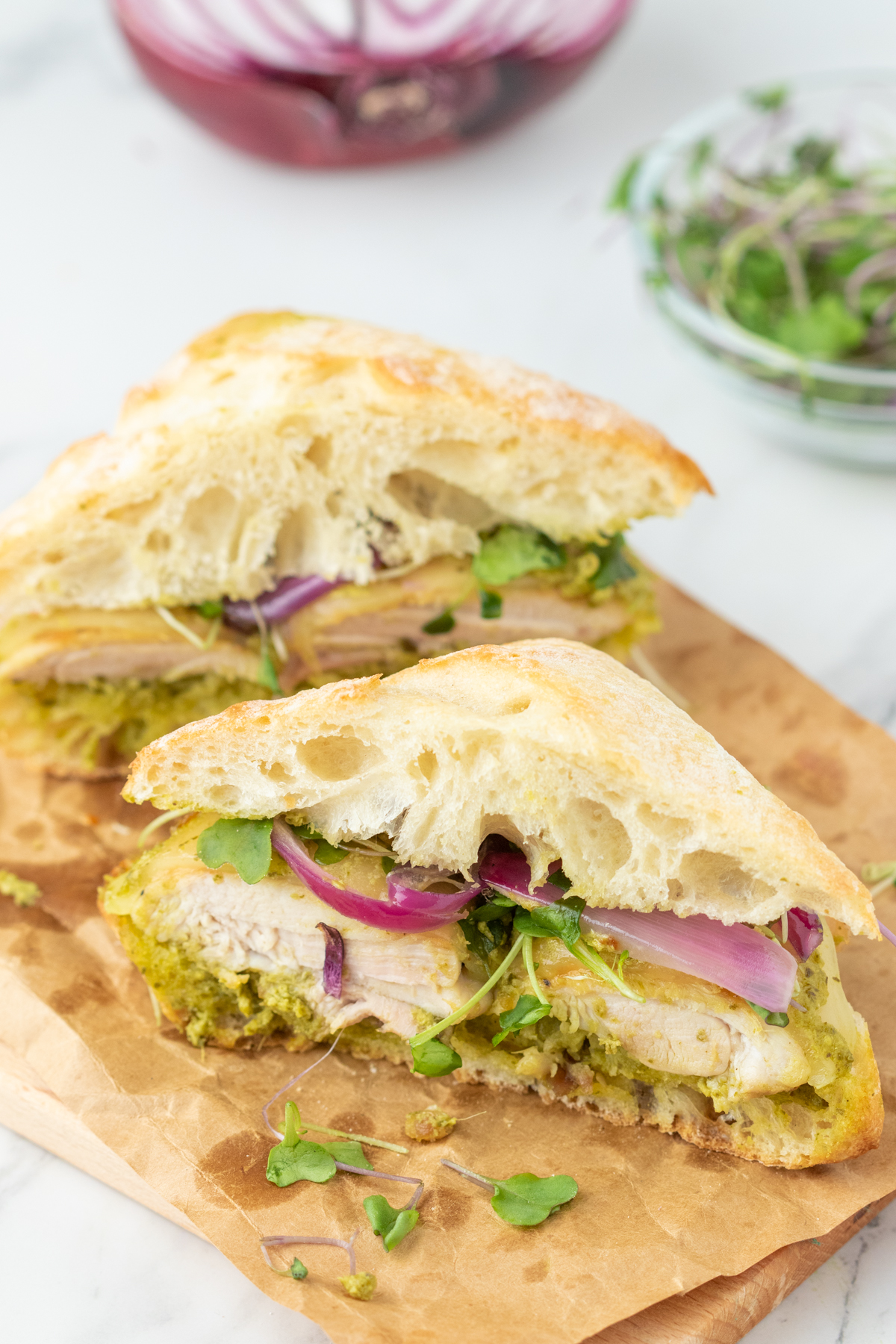 A pesto chicken sandwich cut in half. 