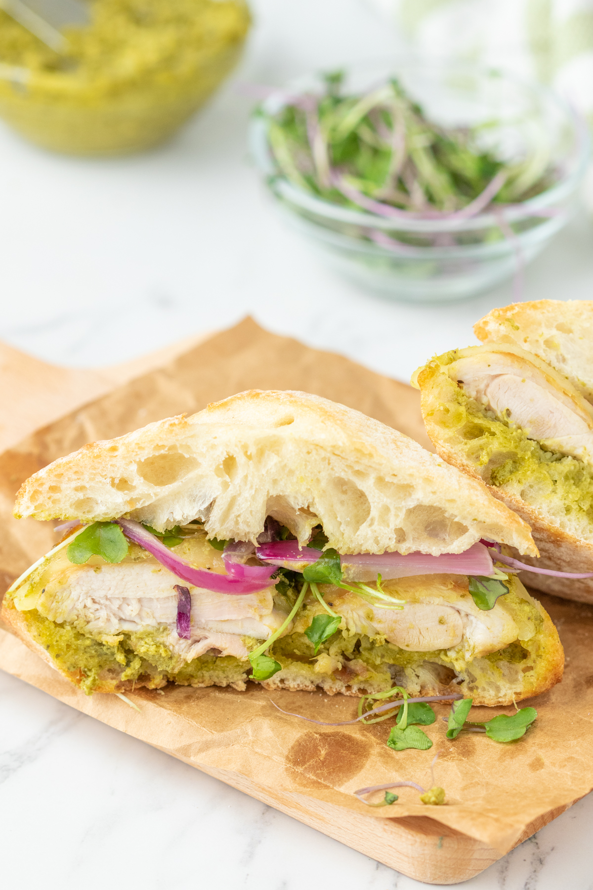 A pesto and chicken breast sandwich, cut in half. 