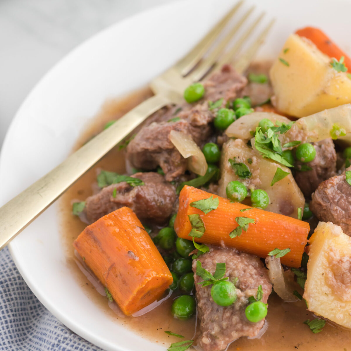 Old fashioned slow cooker beef stew in a white bowl with a fork.