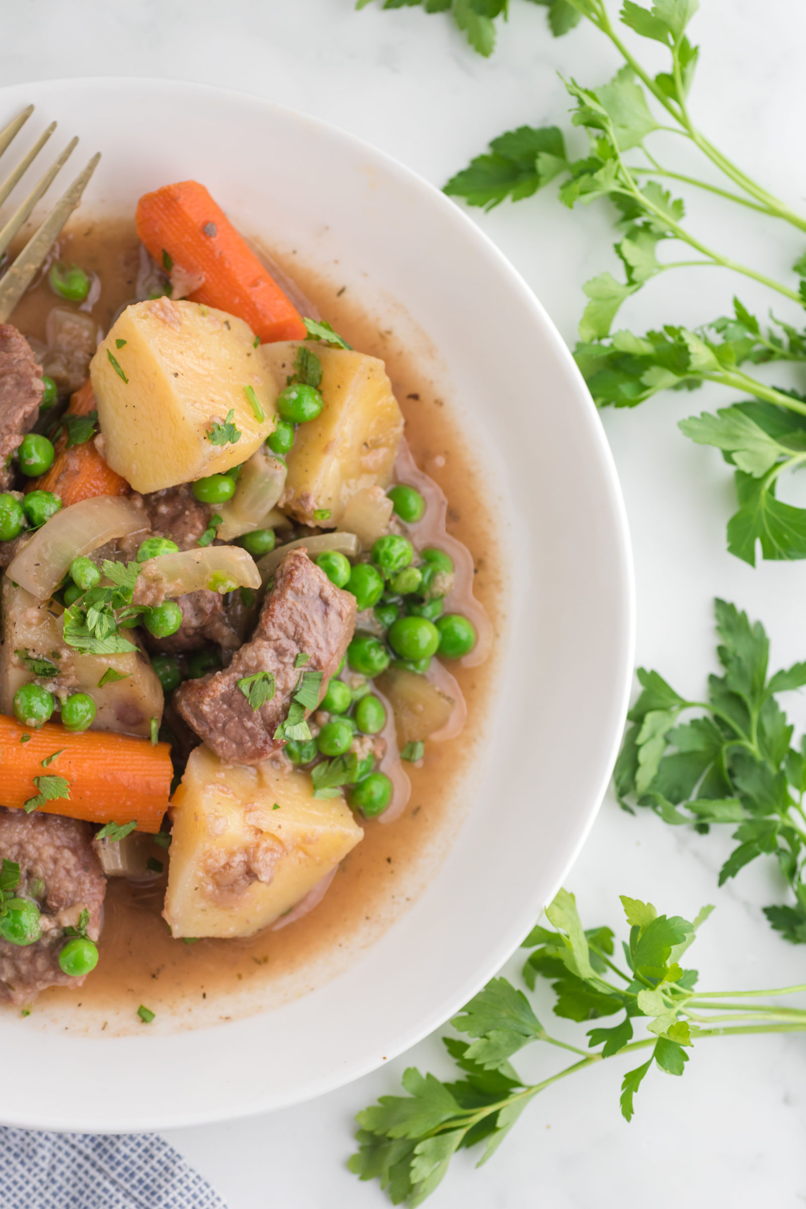 An overhead view of beef stew made without wine in a white bowl. 