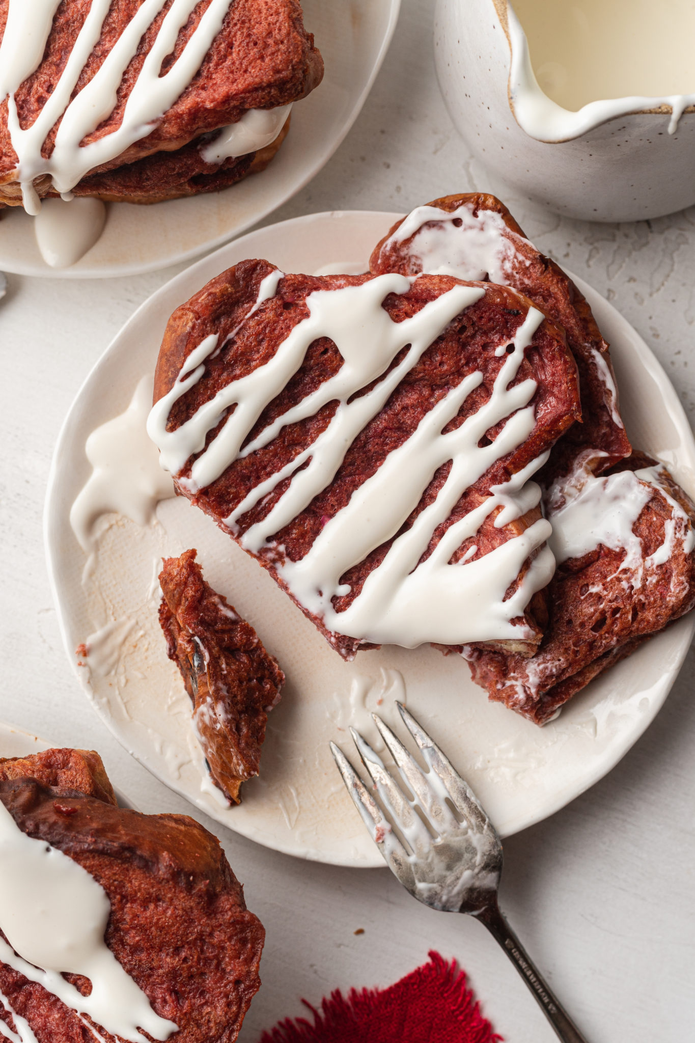 A slice of red velvet french toast topped with cream cheese drizzle.
