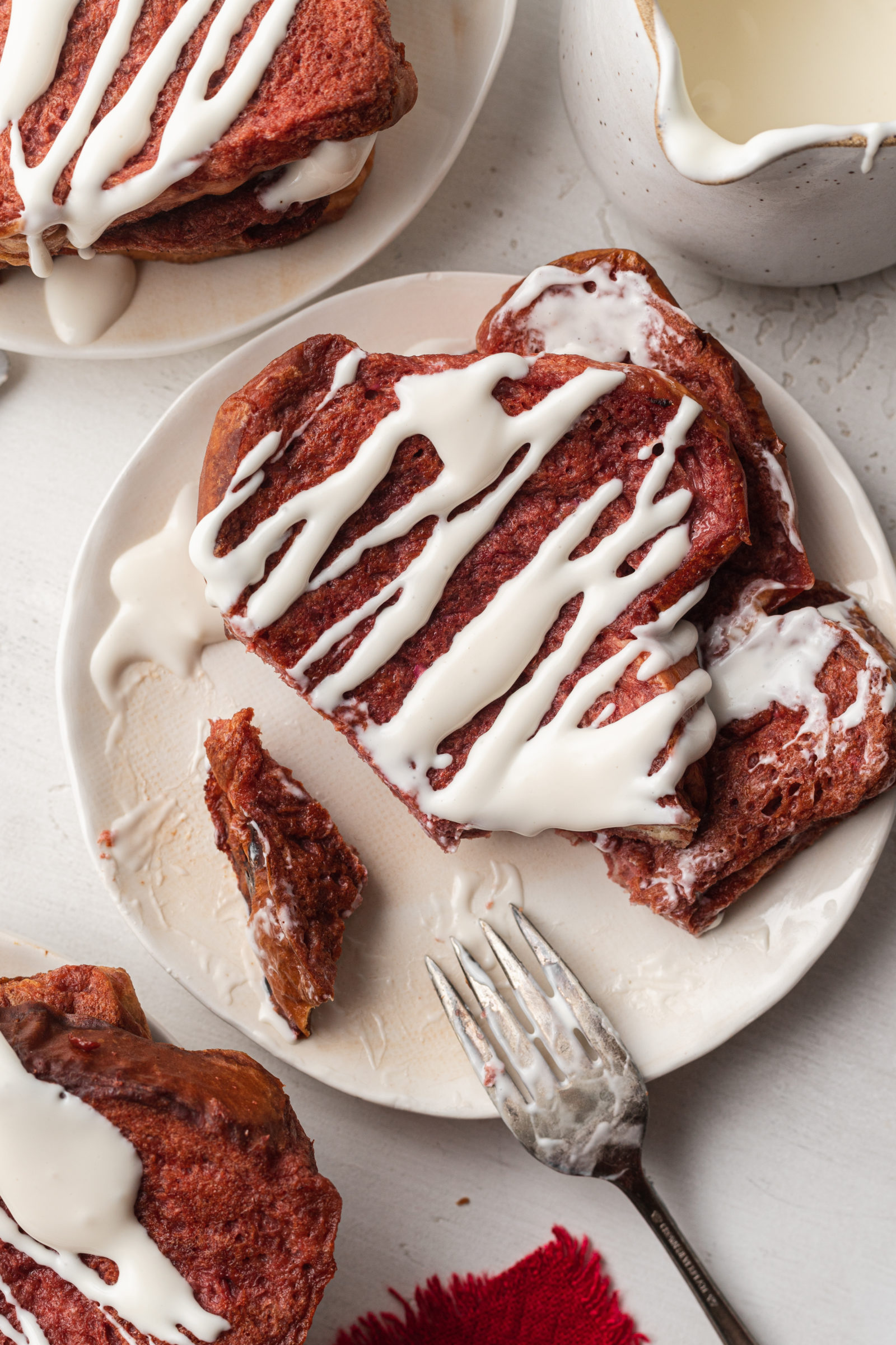 A slice of red velvet french toast topped with cream cheese drizzle. 