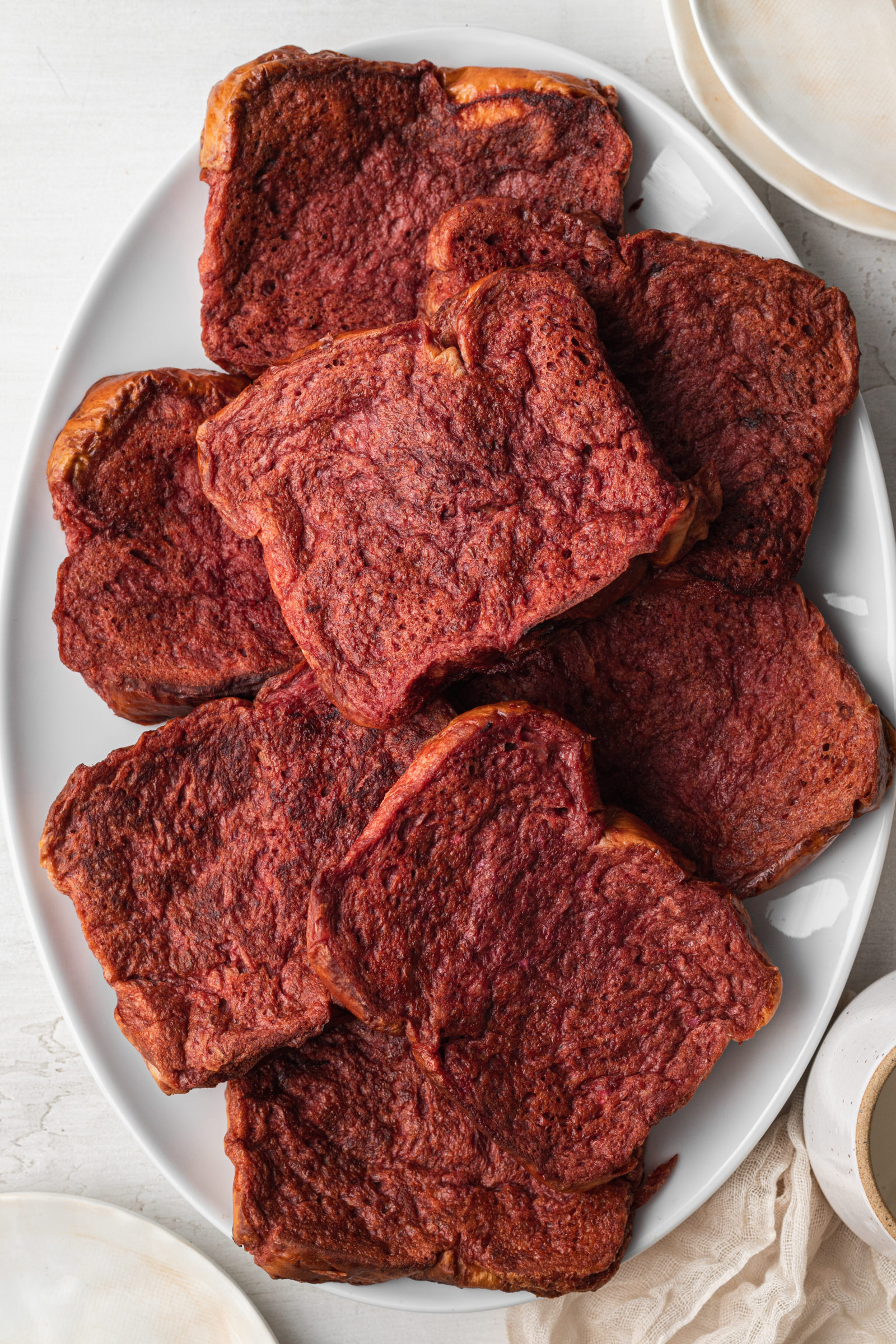 An overhead view of a platter of red velvet french toast slices. 