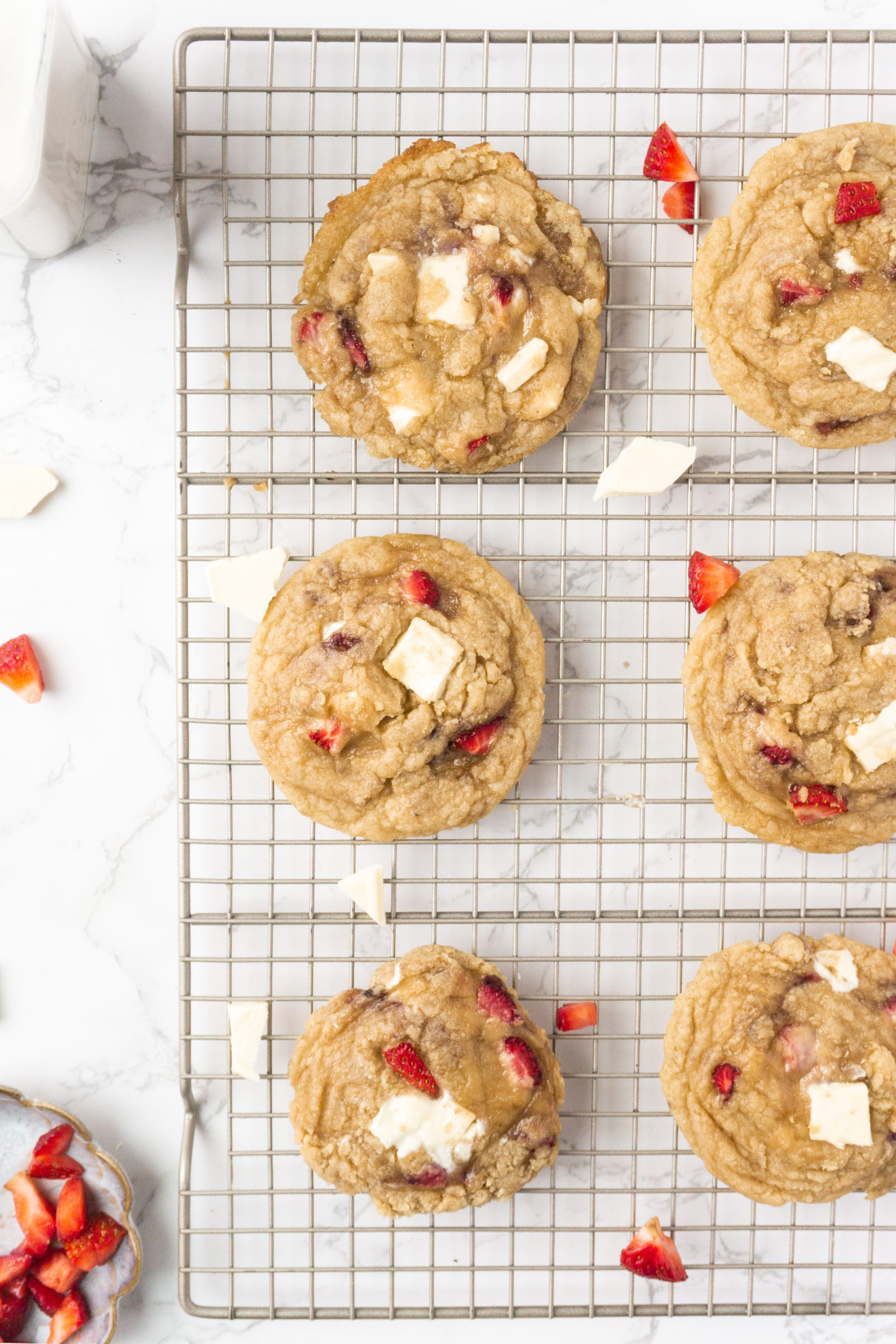 An overhead view of white chocolate chip strawberry cookies cooling on a wire cooling rack. 