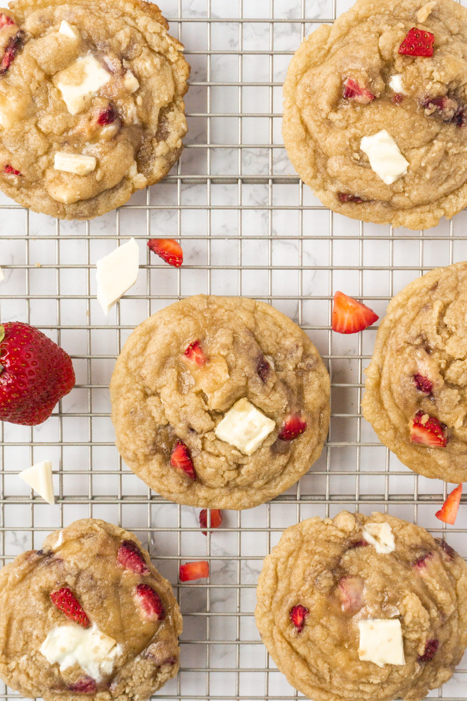 An overhead view of fresh strawberry cookies cooling on a wire cooling rack. 